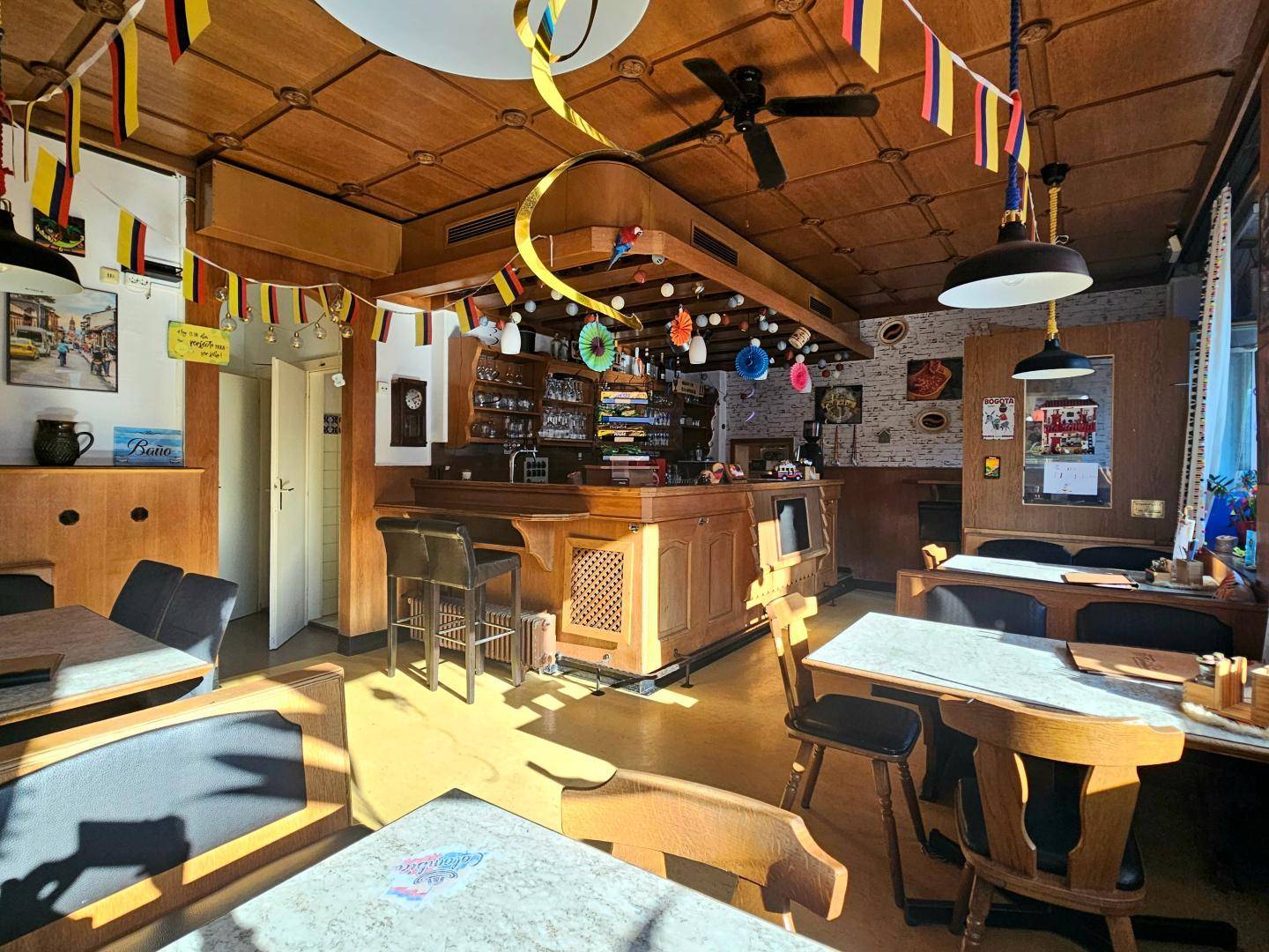 Hauptgastraum mit Bar, Holzelementen, Deckenventilatoren und festlicher Dekoration.