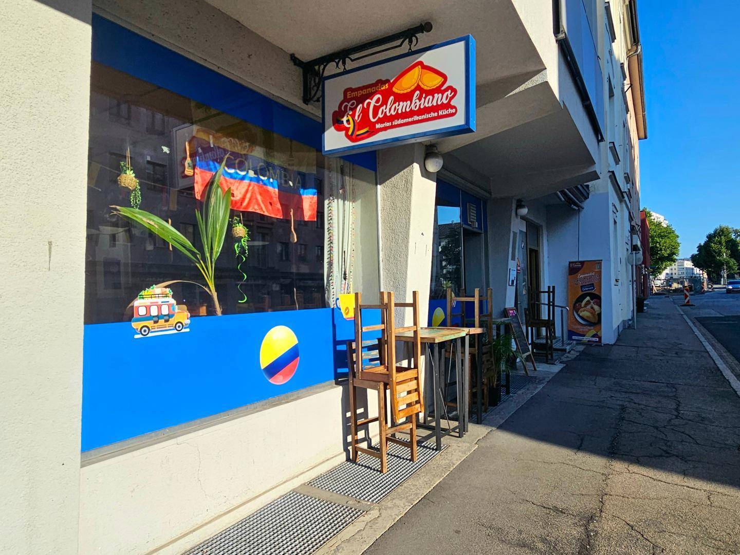Nahaufnahme der Restaurantfassade mit Schaufensterdekoration, Außentischen und Stühlen auf dem Bürgersteig.