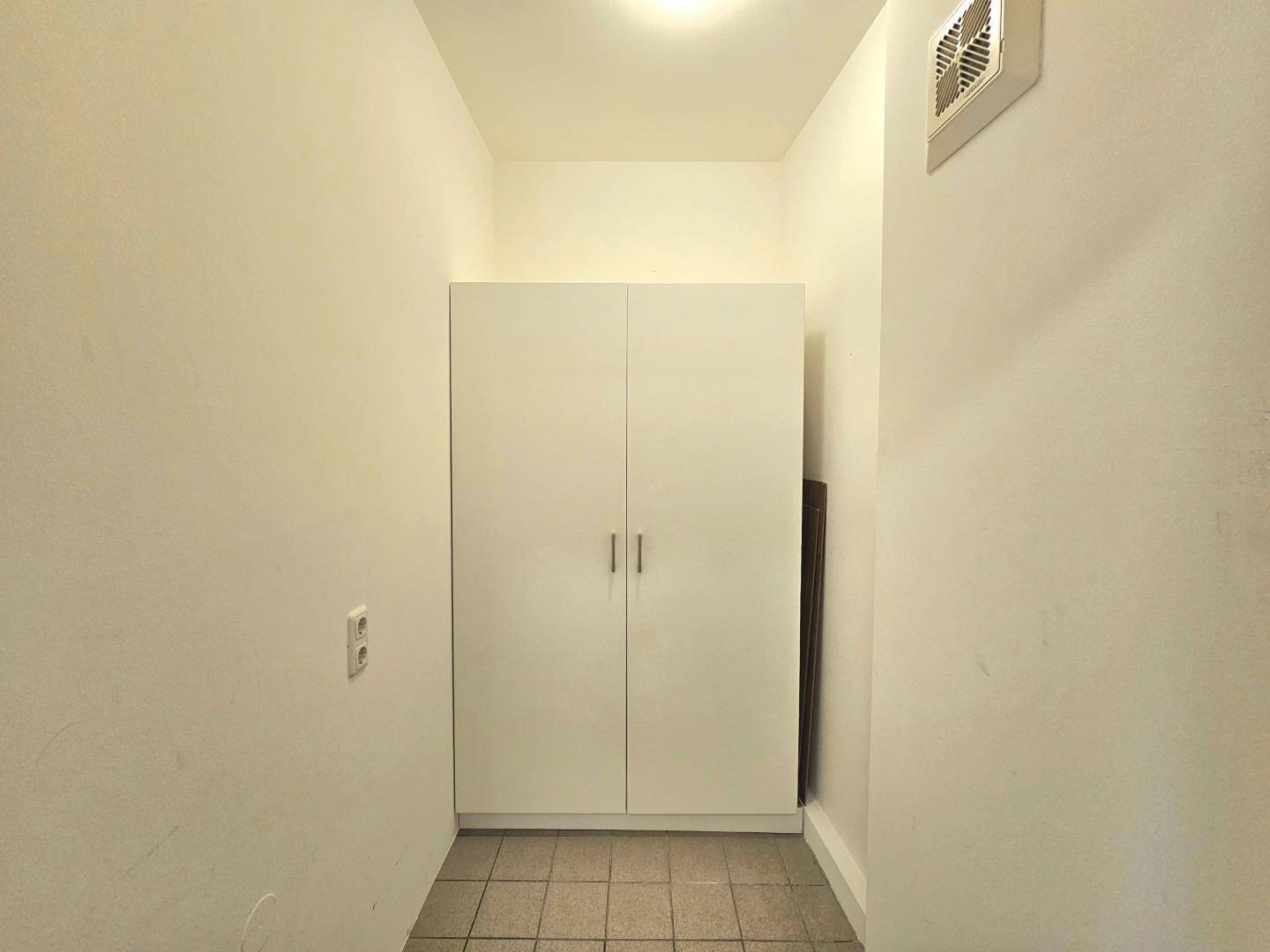 Schmaler Flur mit Fliesenboden und einem praktischen Einbauschrank für zusätzlichen Stauraum.