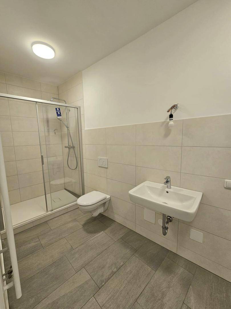 Modernes Badezimmer mit ebenerdiger Dusche, Wand-WC und einem einzelnen Waschbecken.