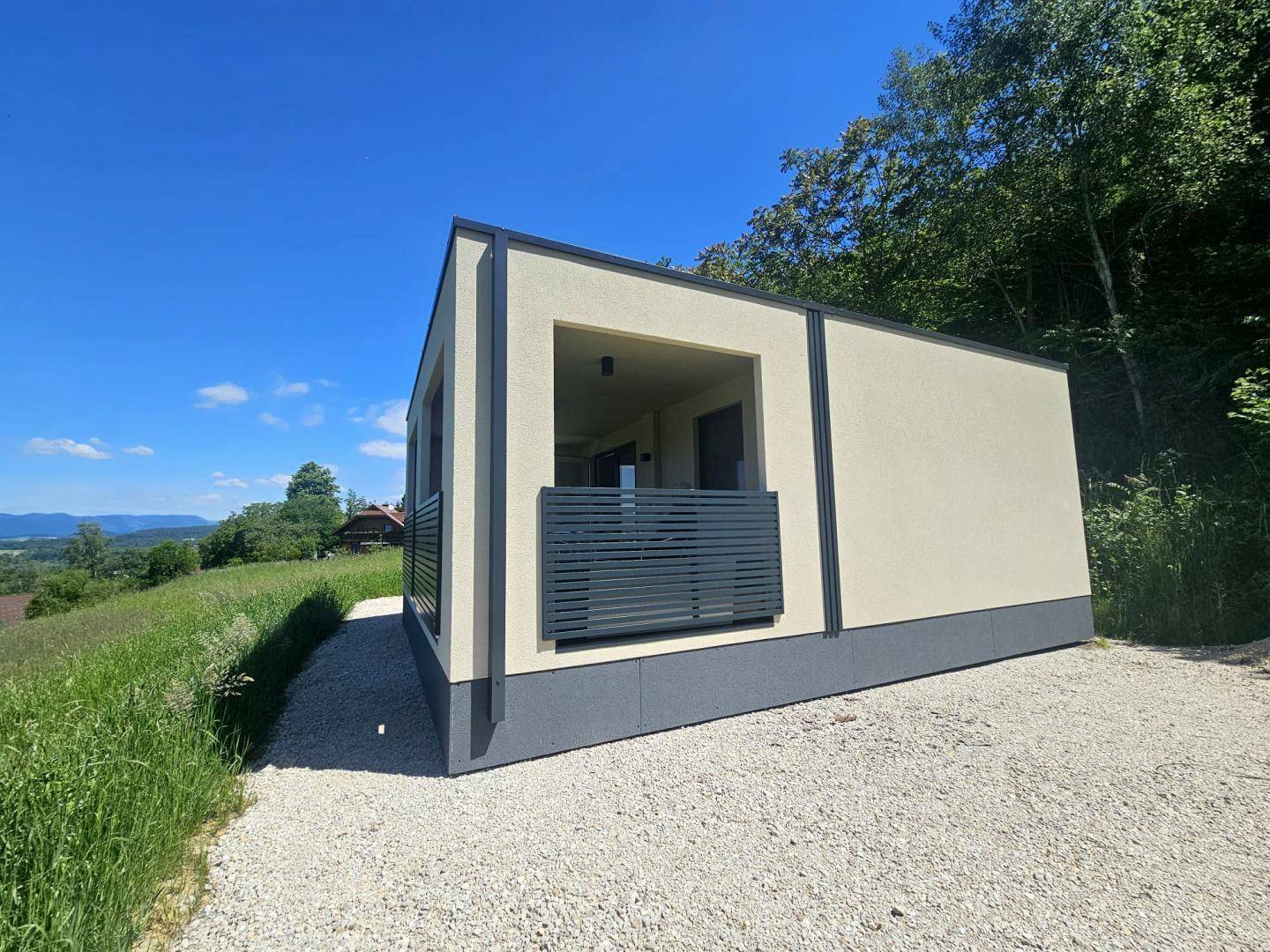 Seitenansicht des Hauses mit Loggia und weitem Blick über die grüne Landschaft.