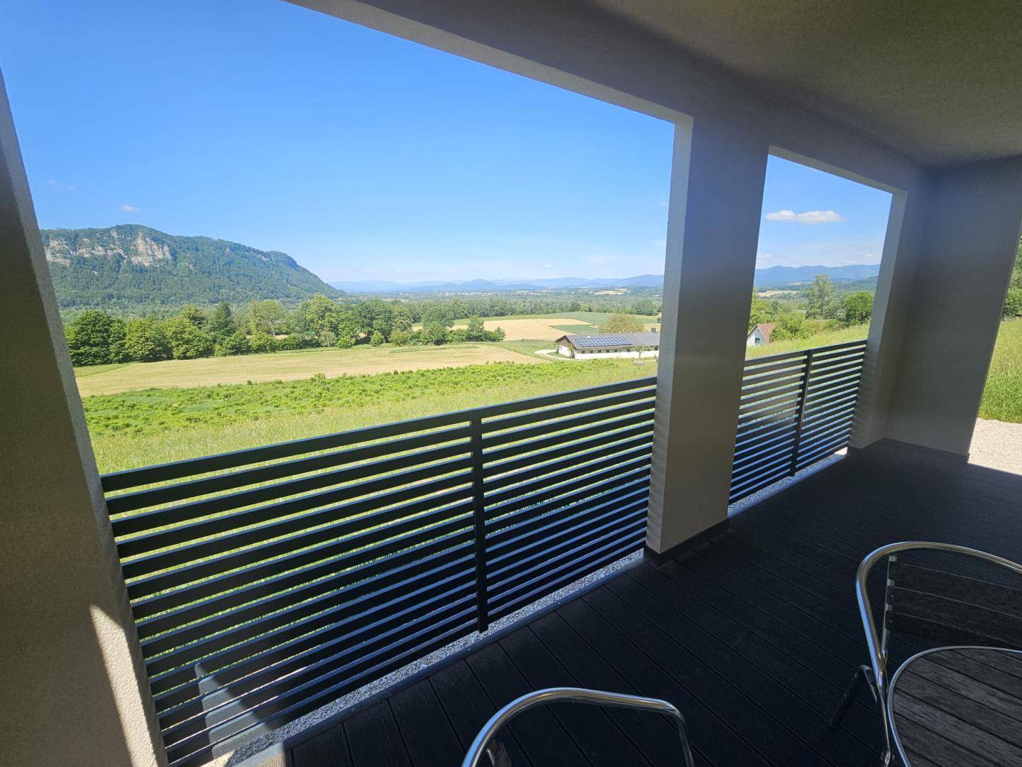 Weitläufiger Blick von der Loggia über Felder und Hügel unter blauem Himmel.