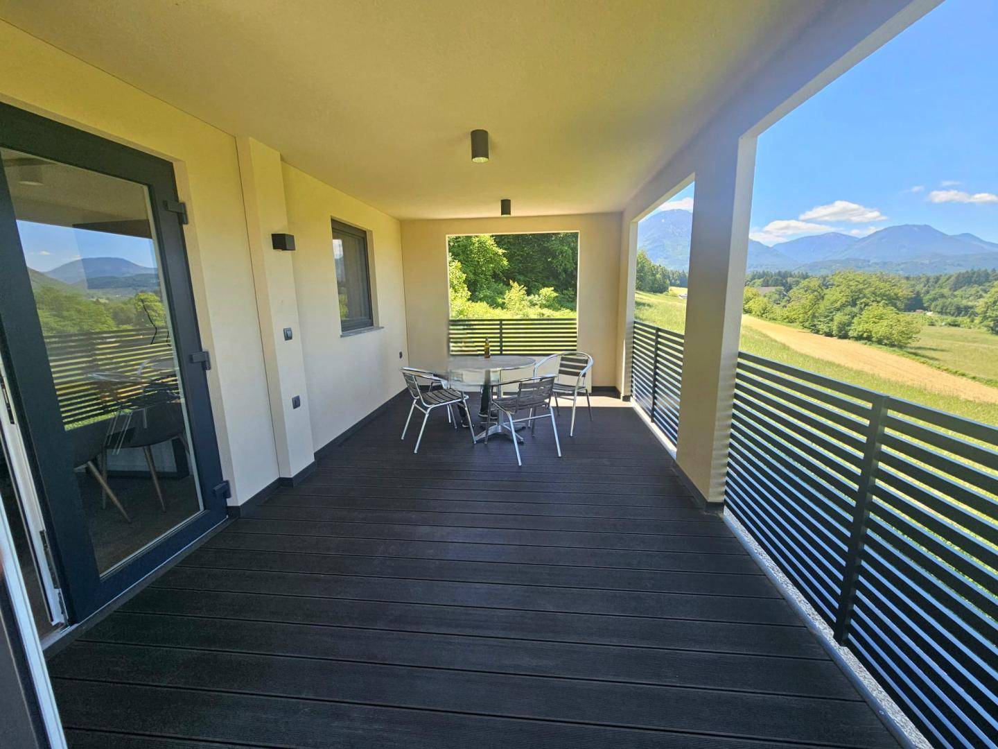 Überdachte Loggia mit Esstisch und Stühlen, bietet einen weiten Blick auf die Landschaft.