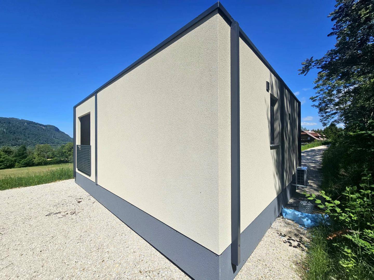 Klare Linien und beige Fassade eines modernen Fertighauses in ländlicher Umgebung.
