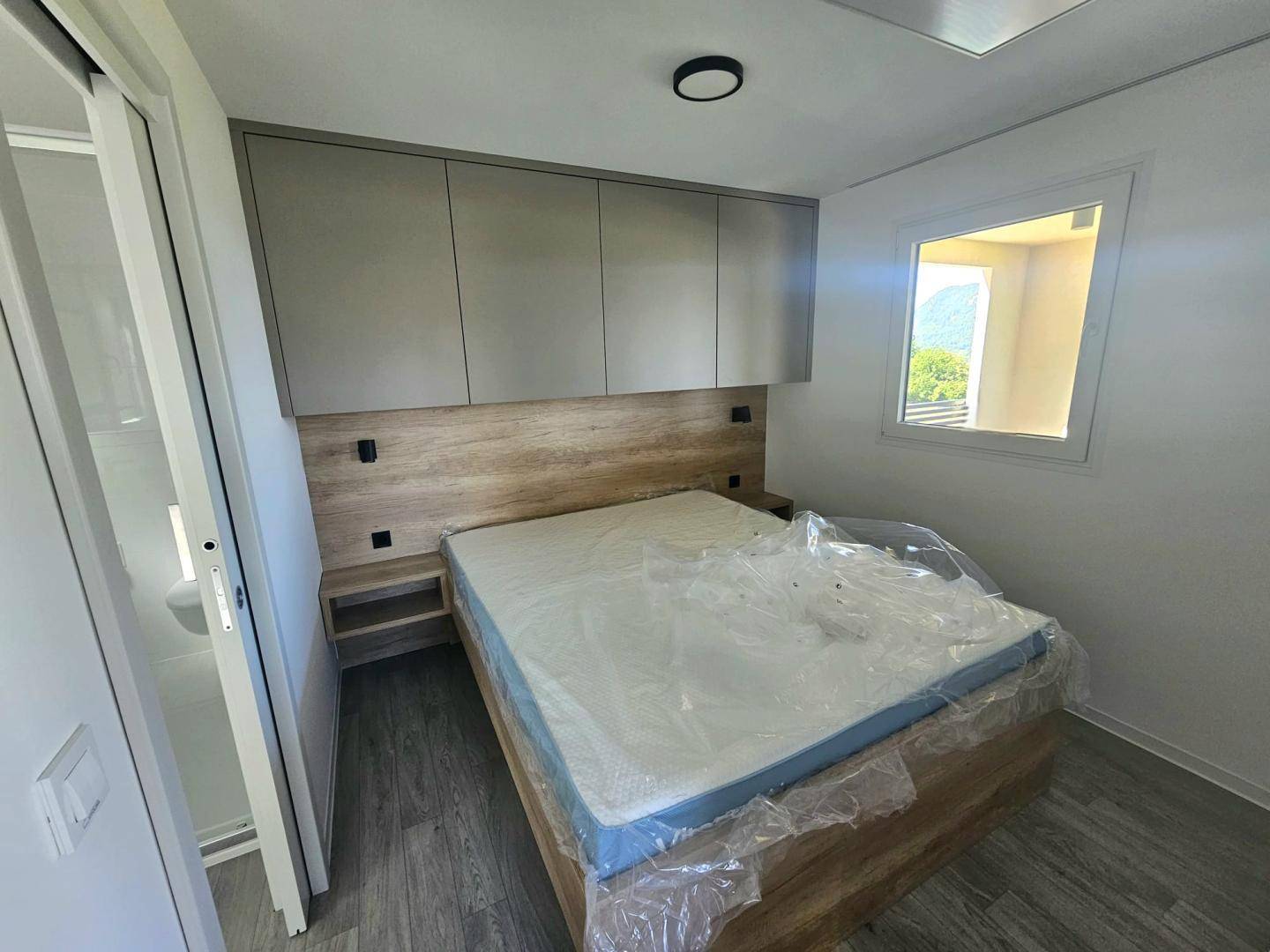 Schlafzimmer mit Doppelbett, integrierten Schränken und Fenster mit Blick ins Grüne.