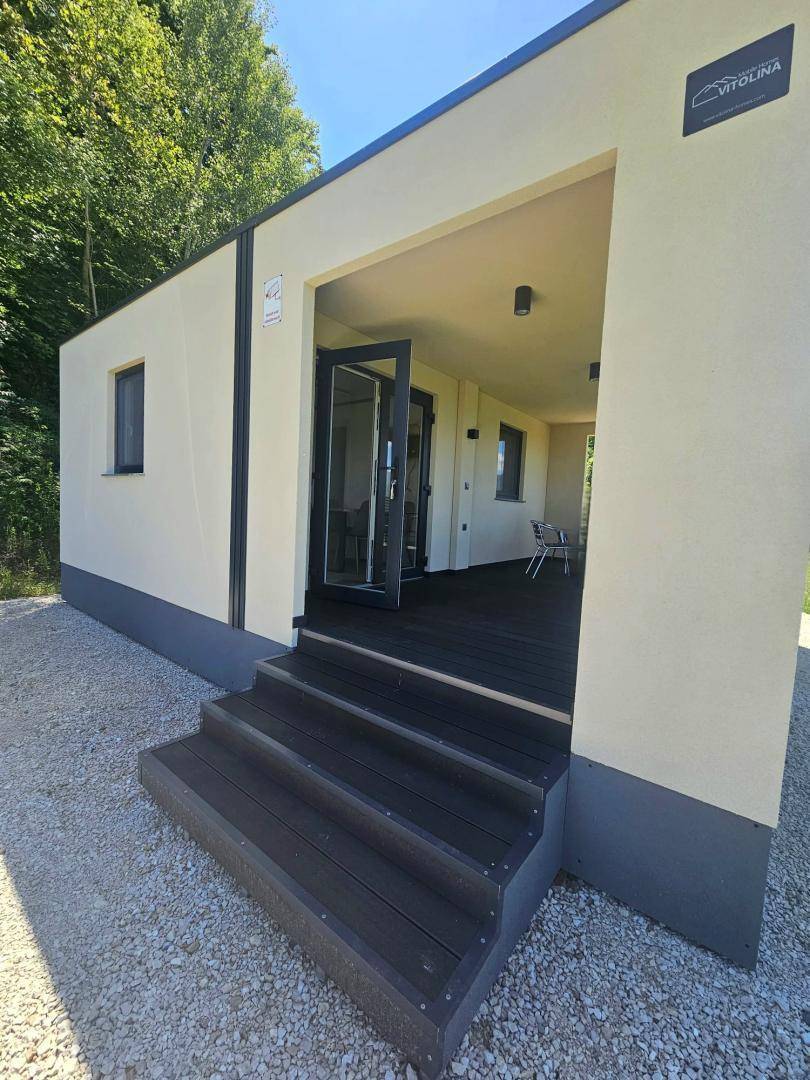 Eingangsbereich des Hauses mit dunklen Holzstufen und überdachtem Zugang zur Terrasse.