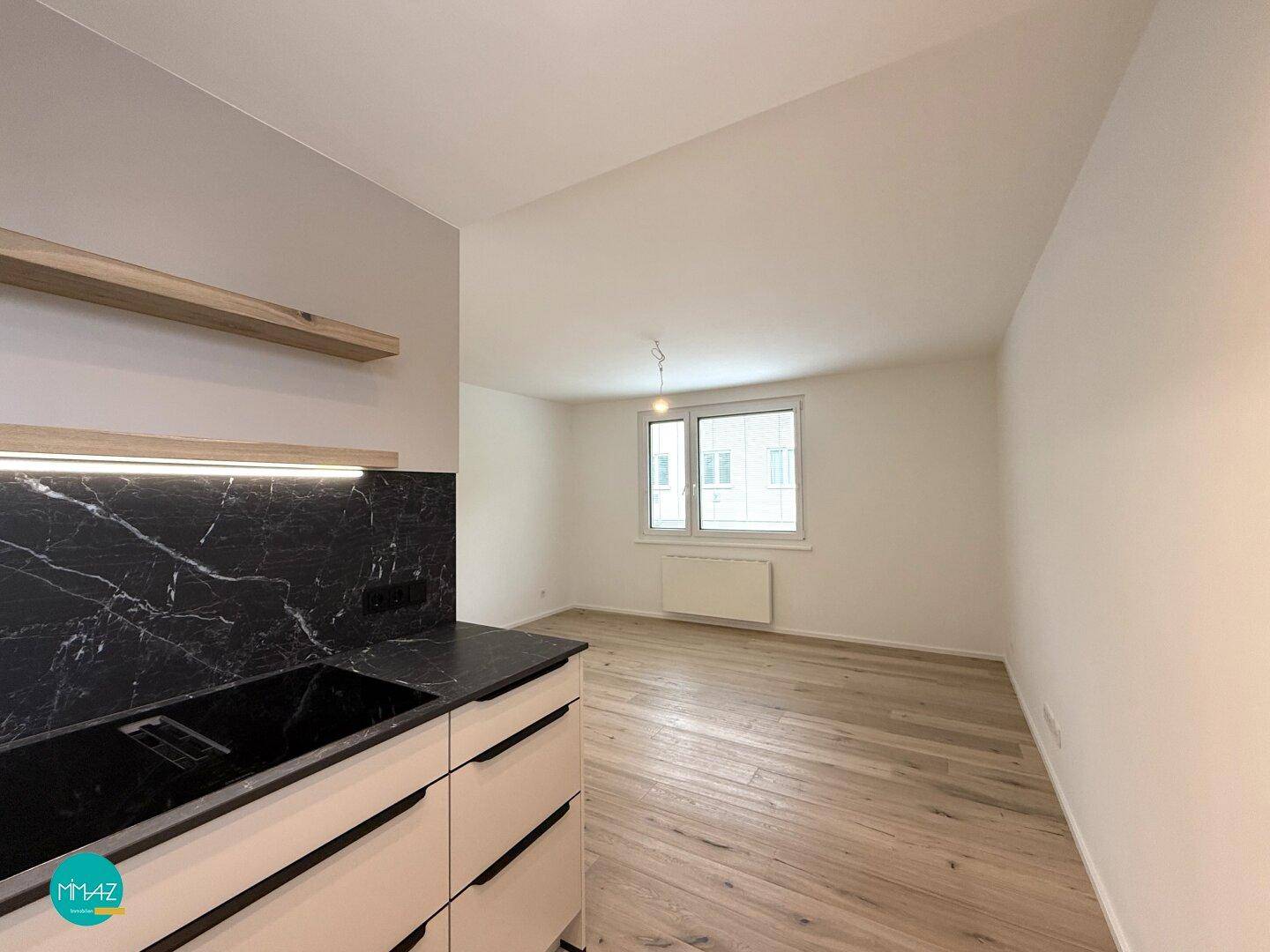 Offener Wohnbereich mit Holzboden und Blick auf die Umgebung durch das Fenster.