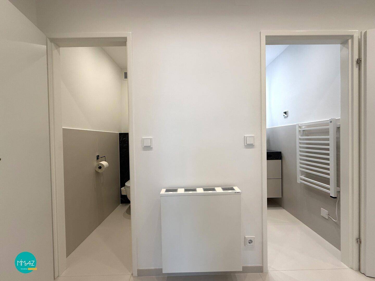 Flur mit Zugang zu separatem WC und Badezimmer, ausgestattet mit modernen Fliesen.