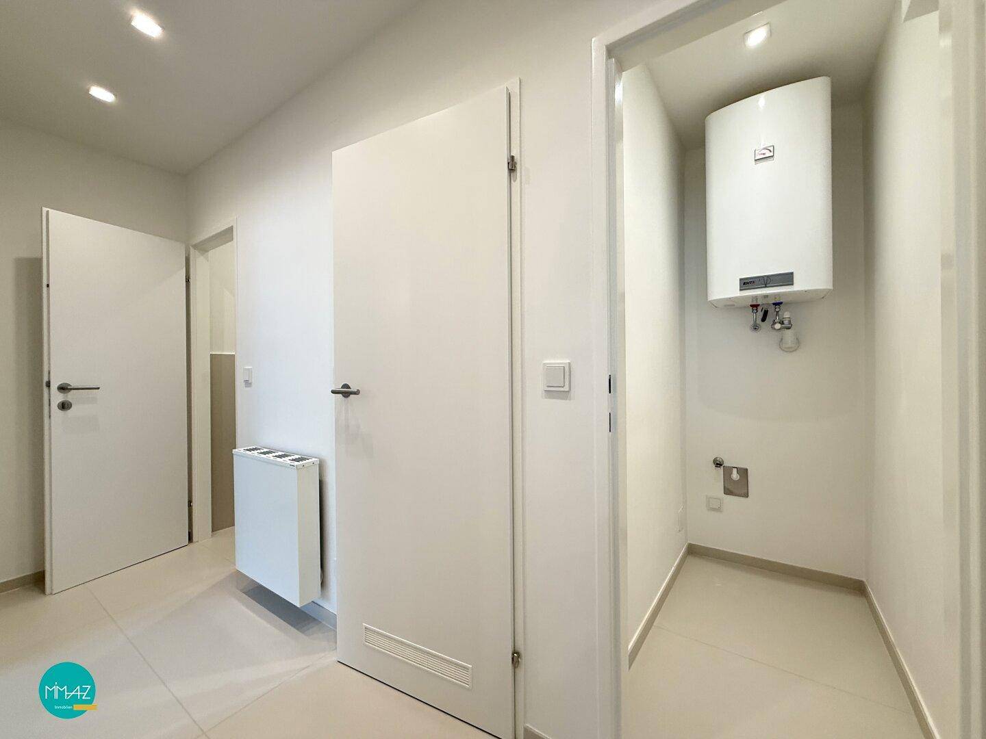 Praktischer Hauswirtschaftsraum mit Warmwasserboiler und Anschlüssen für Waschmaschine.