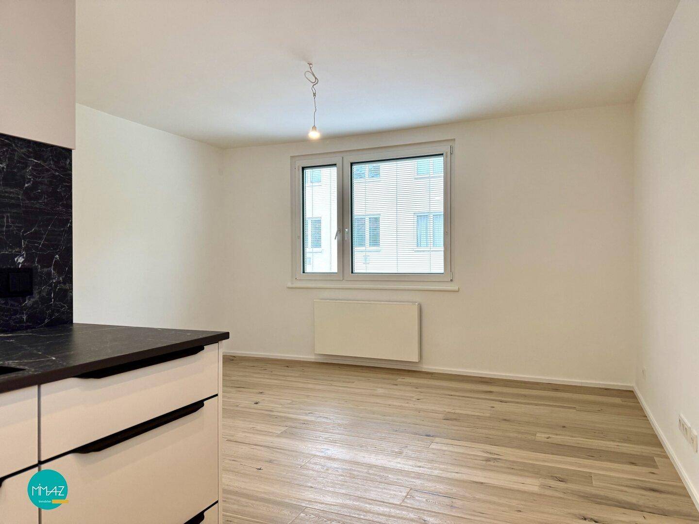 Helles Schlafzimmer mit Parkettboden und großem Fenster, bereit zur individuellen Gestaltung.