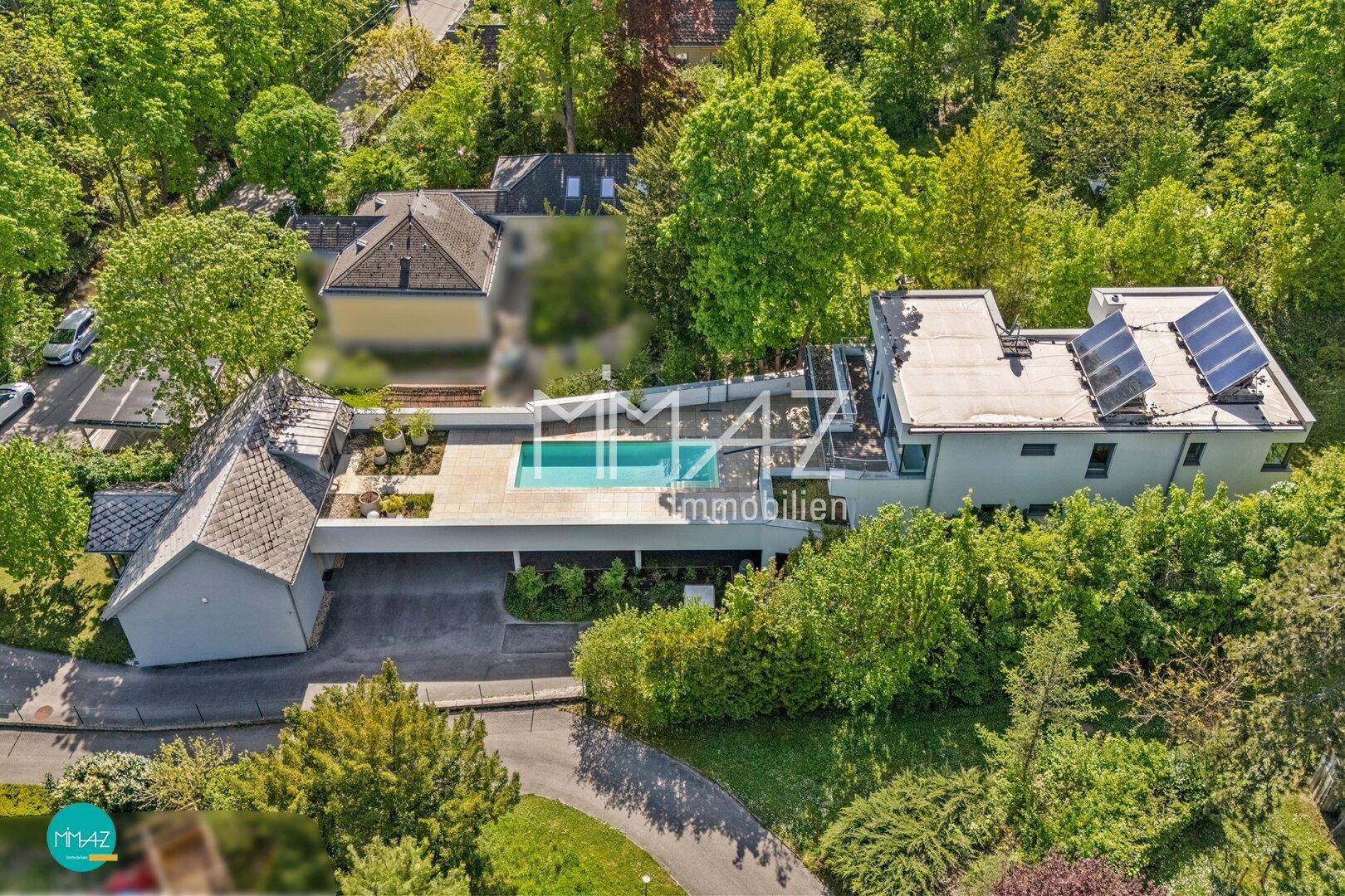 Luftaufnahme eines modernen Anwesens mit Pool, Solaranlage auf dem Dach und viel Grün.