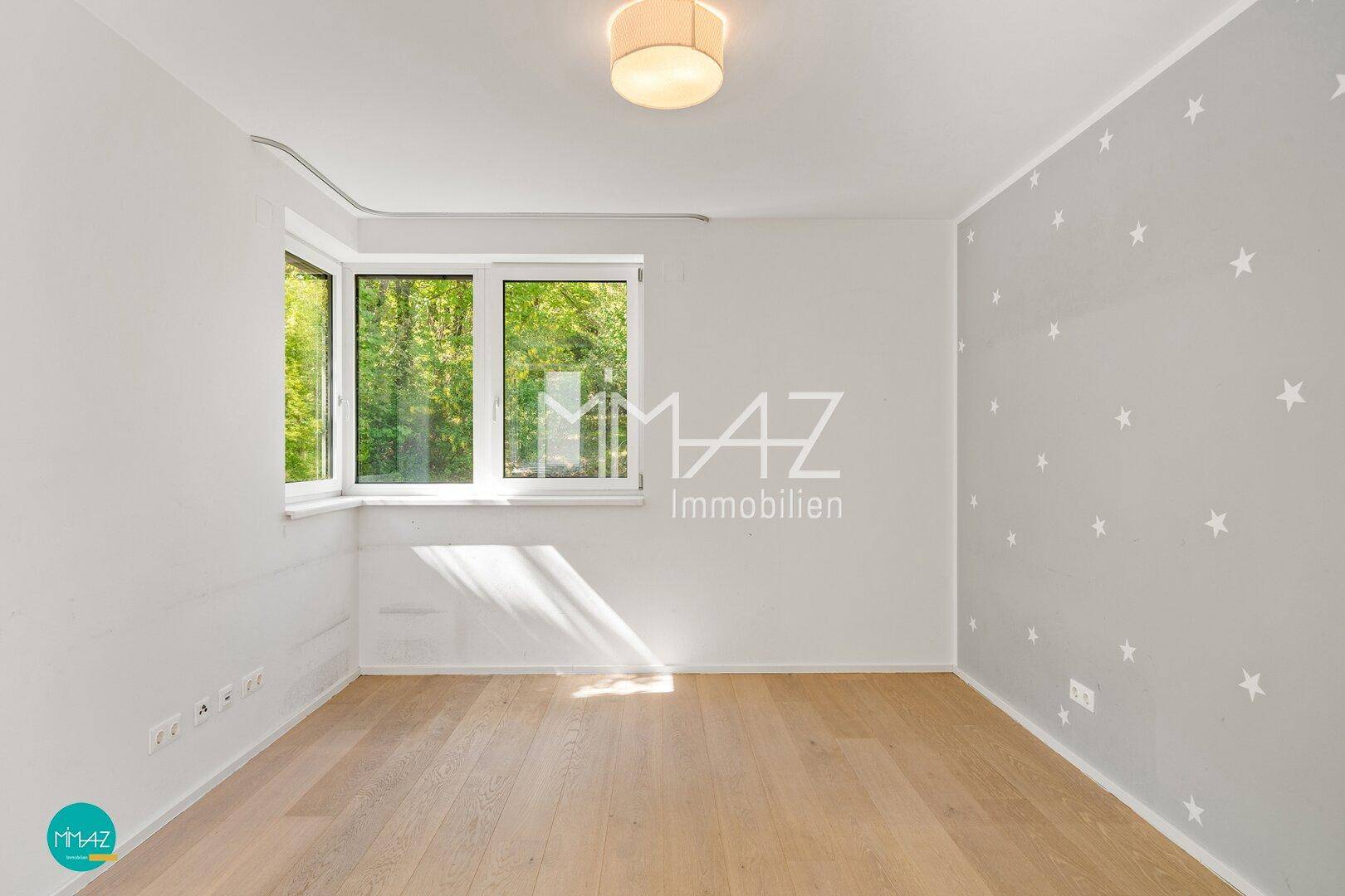 Helles Schlafzimmer mit Holzboden, Sternen-Tapete und großen Fenstern mit Blick ins Grüne.