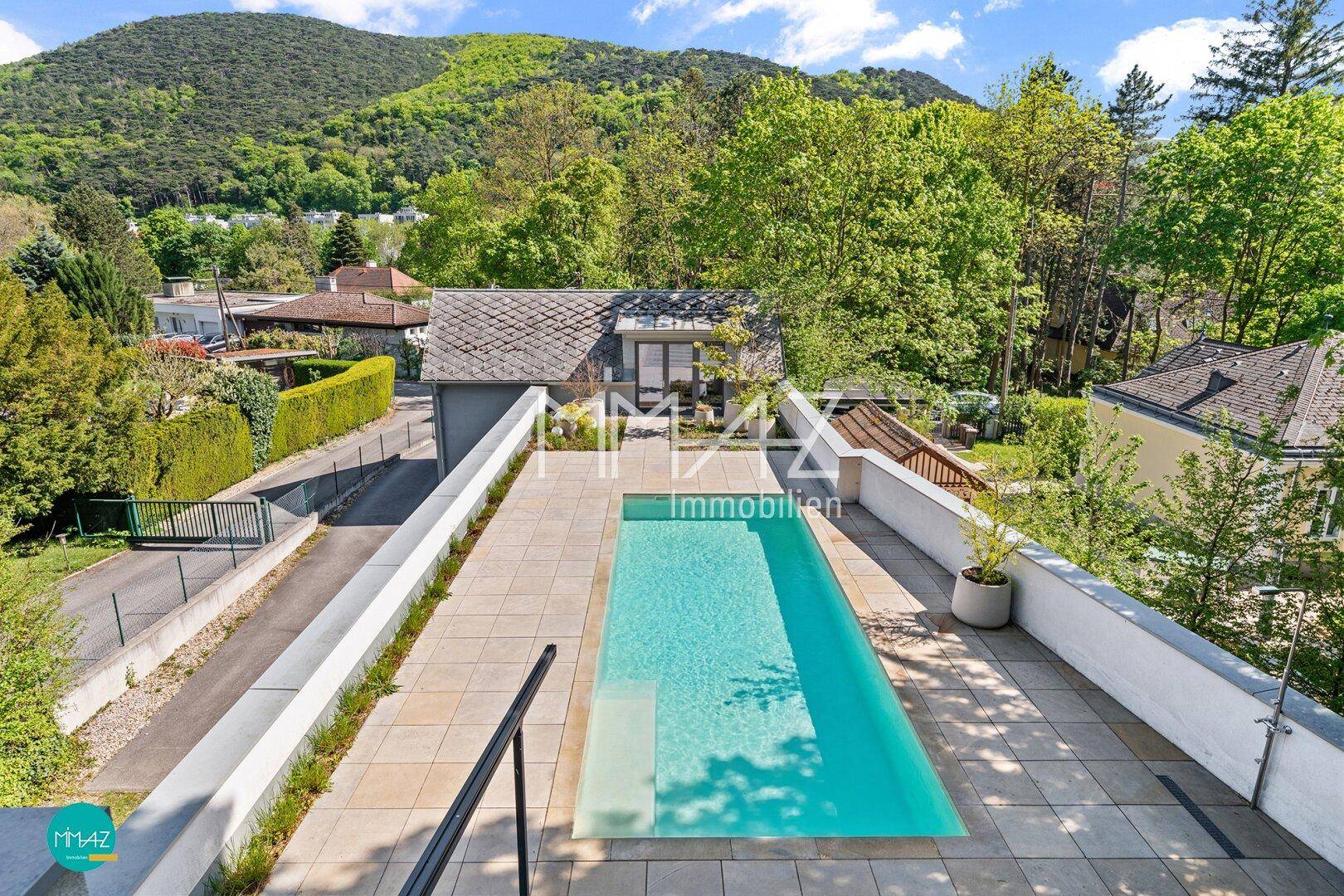 Außenpoolbereich mit gepflasterter Terrasse und weitem Blick auf die umliegende Berglandschaft.