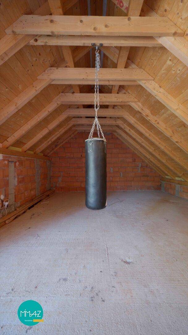 Ausgebauter Dachboden mit Holzbalken und Boxsack, ideal für Sport oder Hobby.