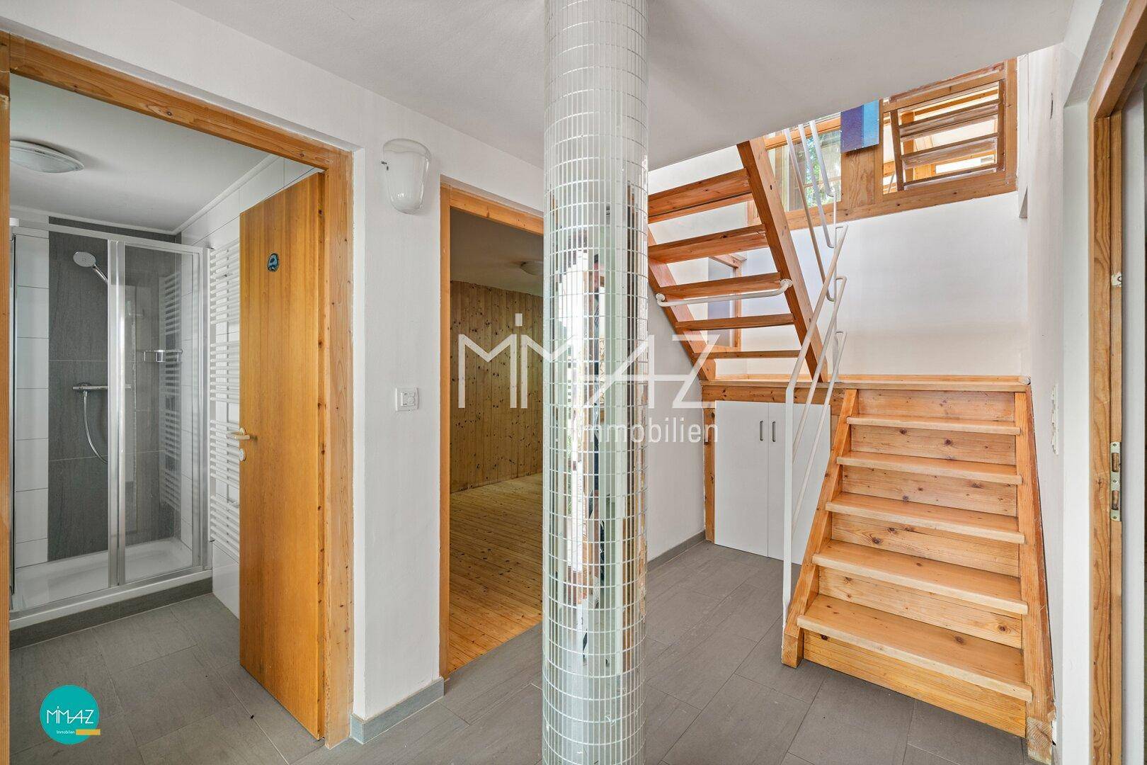 Flur mit Holztreppe, Spiegelsäule und Zugang zu weiteren Räumen und einem Duschbad.