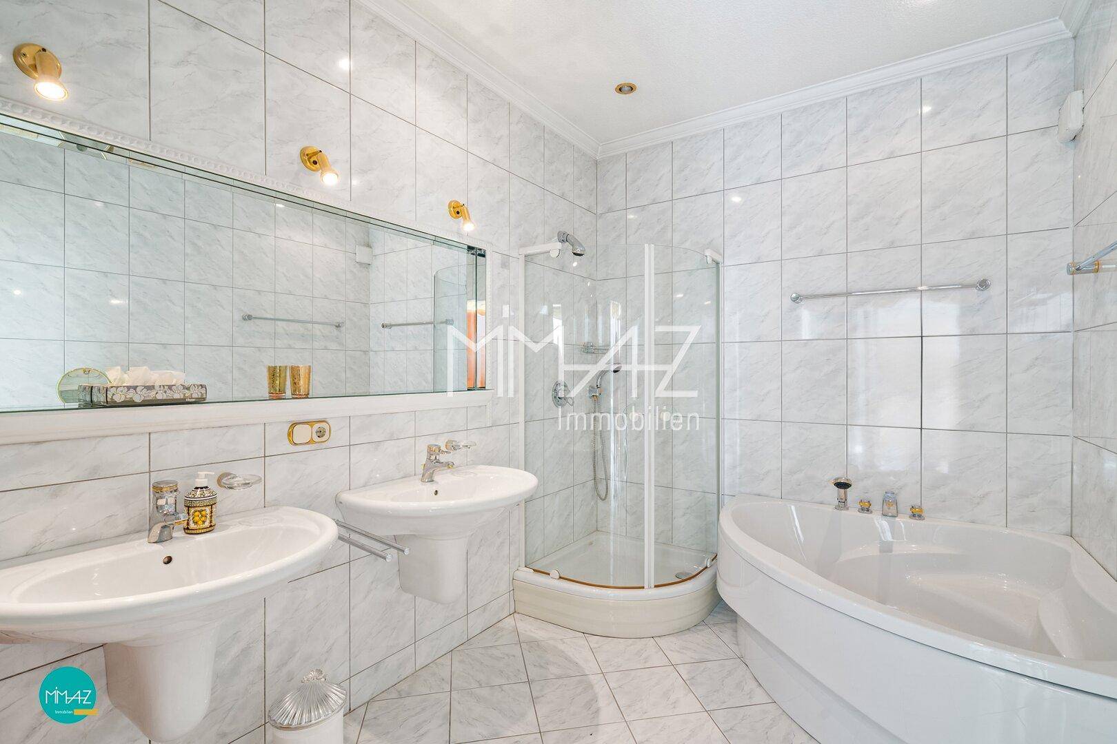 Helles Badezimmer mit zwei Waschbecken, Dusche und Badewanne, komplett gefliest in Weiß.
