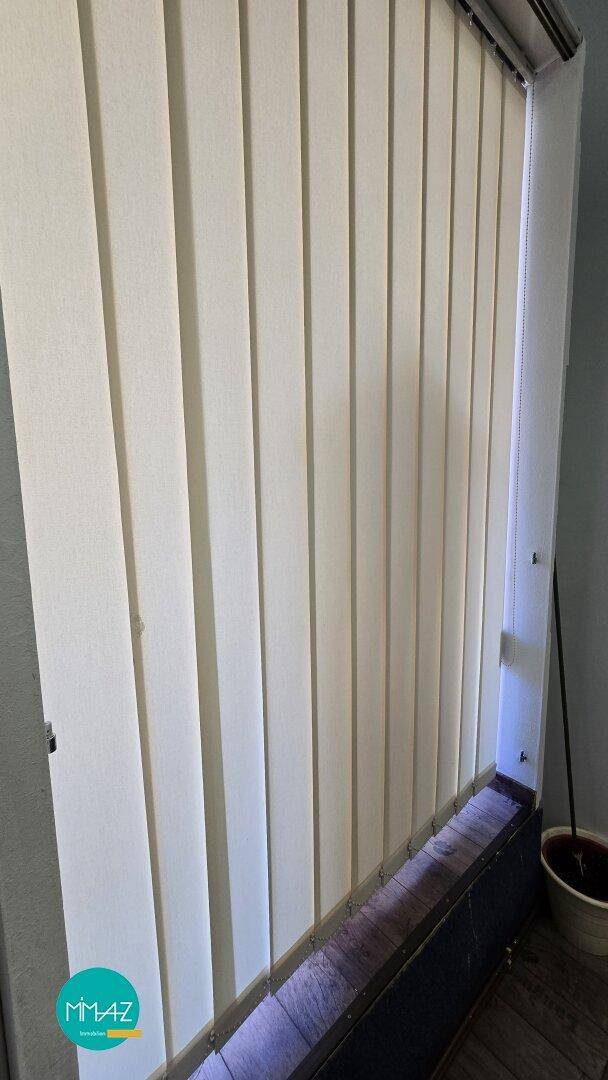 Fenster mit vertikalen Jalousien, die für Privatsphäre und Lichtregulierung sorgen.