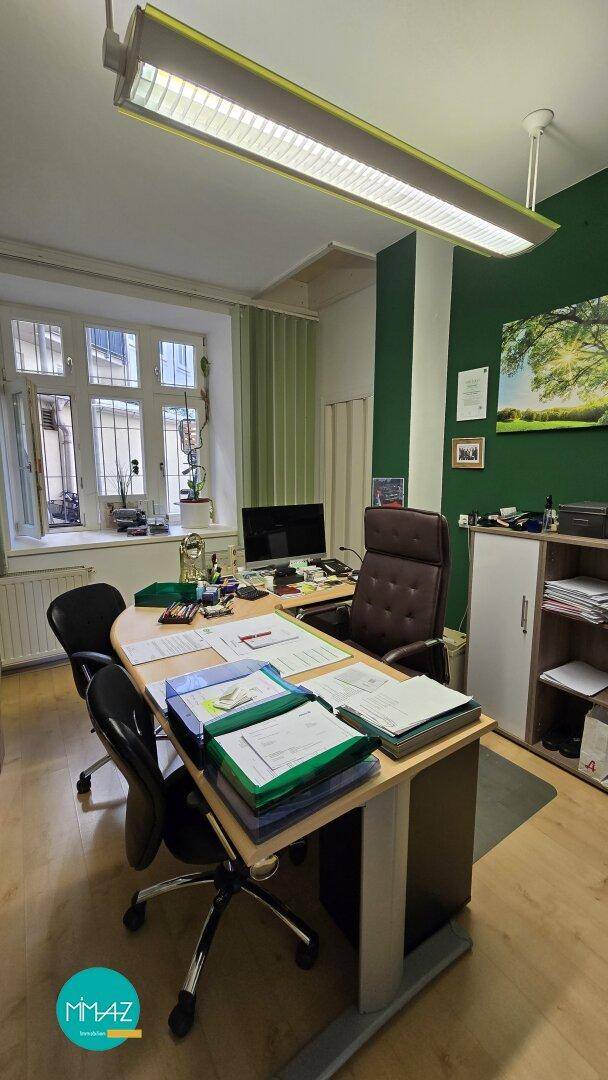Helles Büro mit großem Fenster, Schreibtisch und Deckenleuchte, ideal für konzentriertes Arbeiten.