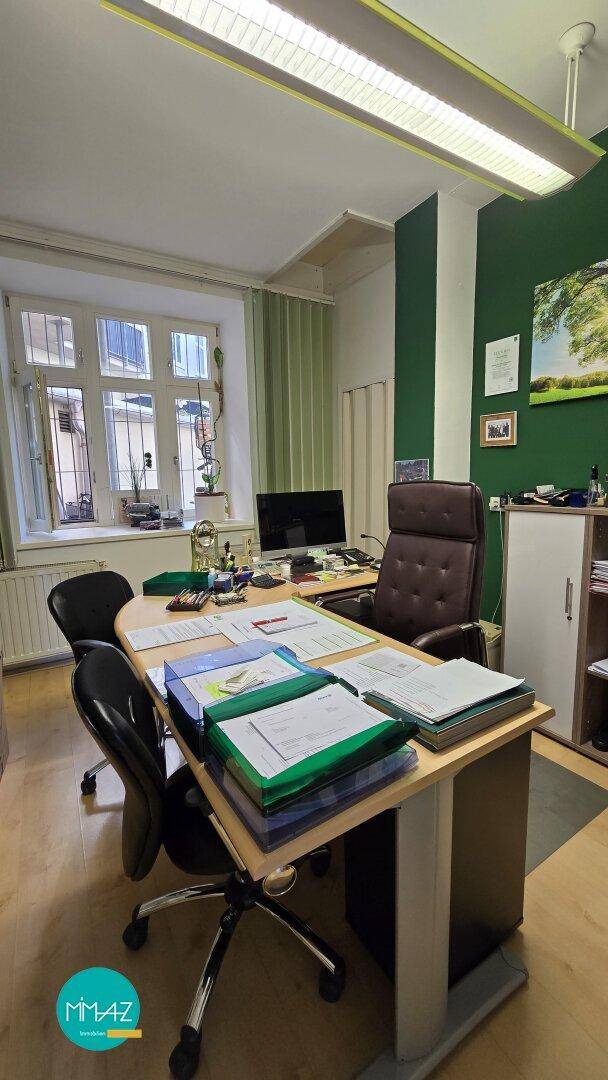 Arbeitsbereich in einem Büro mit großem Fenster, Schreibtisch und Deckenbeleuchtung, gut beleuchtet.