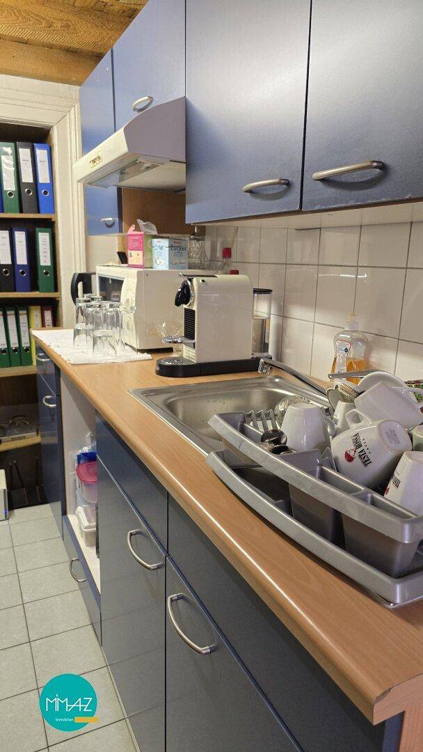 Kleine Küchenzeile mit blauen Schränken, Spüle und Kaffeemaschine, praktisch und kompakt.