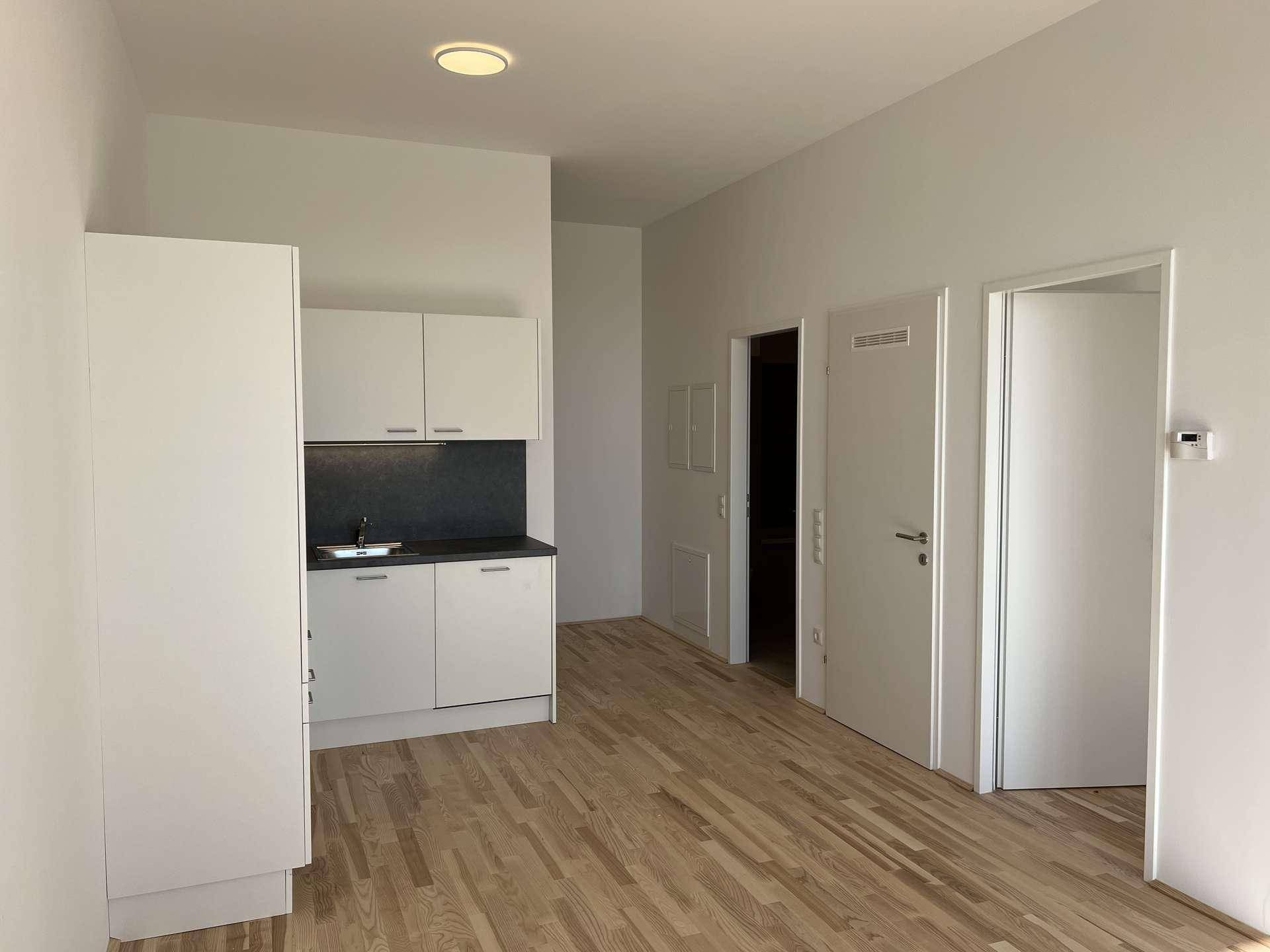 Kleine Küchenzeile in einem hellen Raum mit Holzboden und hoher Decke von 3,05 m.