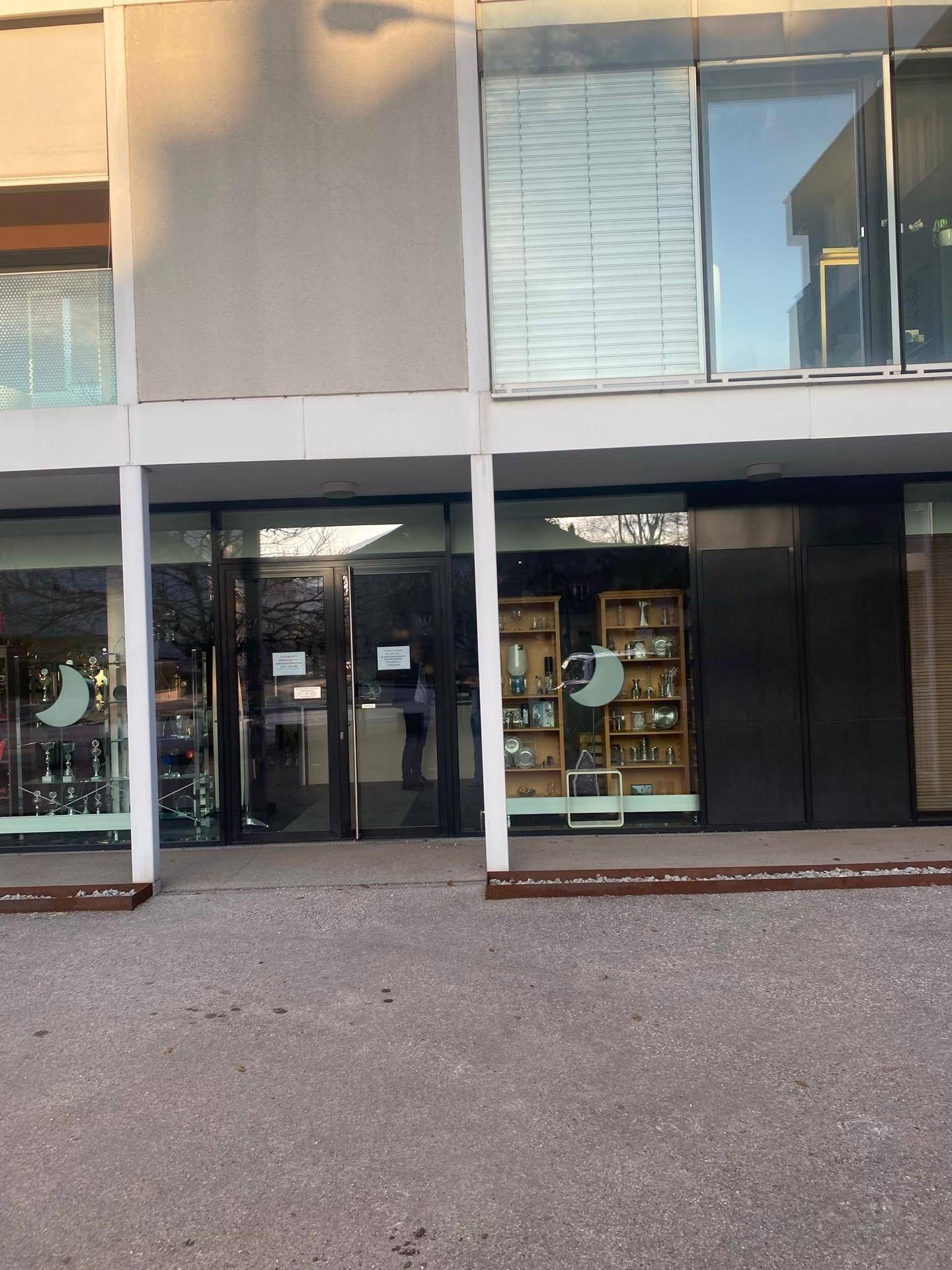 Eingangsbereich des Geschäfts im Erdgeschoss mit Glastüren und großen Schaufenstern.