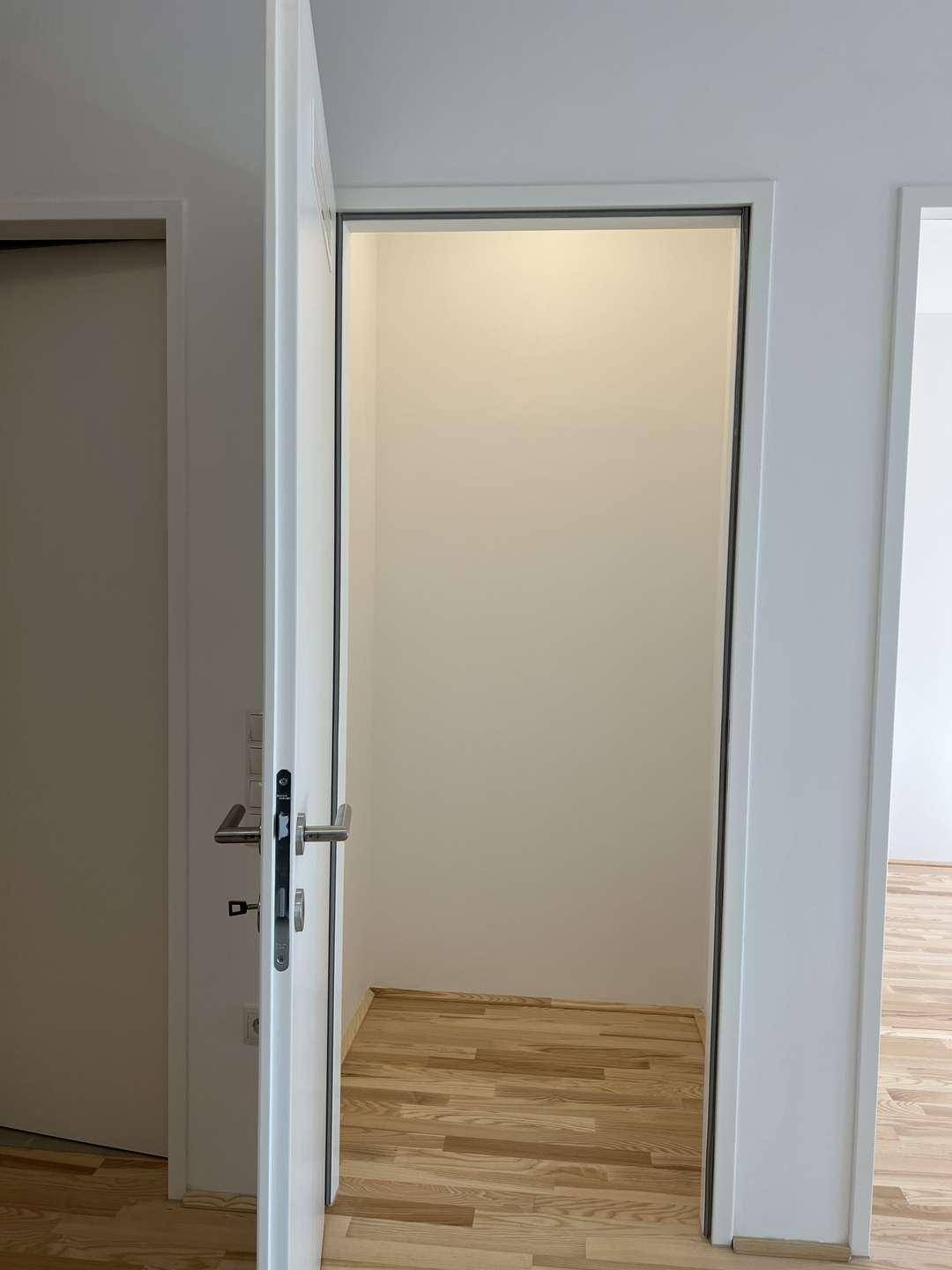 Kleiner Abstellraum mit Holzboden und weiß gestrichenen Wänden.