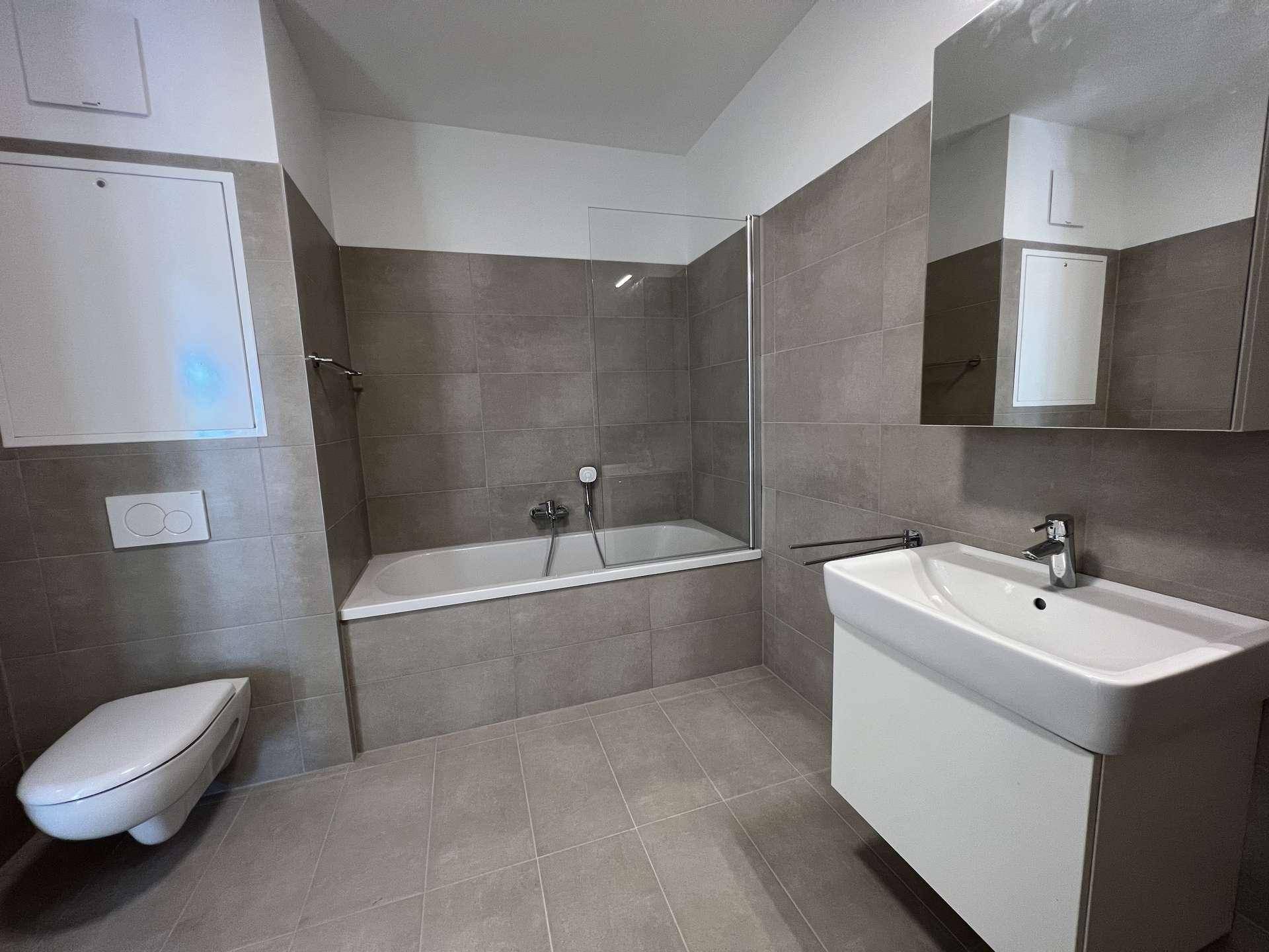 Zeitgemäßes Badezimmer mit Badewanne, Waschtisch und Spiegelkabinett.