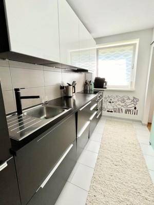Moderne Küche mit schwarzen Unterschränken, weißen Oberschränken und Fenster.