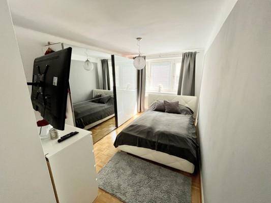 Gemütliches Schlafzimmer mit Einzelbett, Spiegelschrank und Fenster mit Jalousien.
