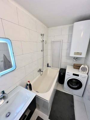 Modernes Badezimmer mit Badewanne, Waschbecken und Waschmaschine.
