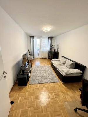 Geräumiges Wohnzimmer mit Parkettboden und viel Tageslicht durch das Fenster.