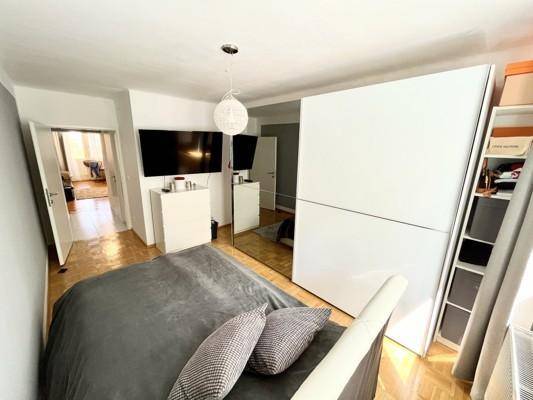 Schlafzimmer mit großem Spiegelschrank und Zugang zu einem weiteren Raum.