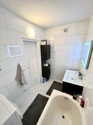 Helles Badezimmer mit modernem Waschbecken, beleuchtetem Spiegel und Stauraum.