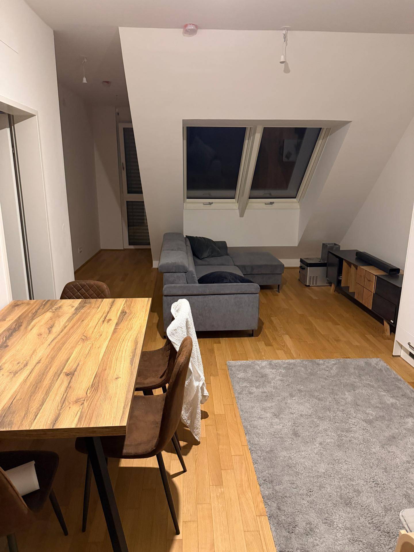 Gemütlicher Wohnbereich mit Esstisch, Sofa und Dachschrägenfenstern, ausgestattet mit Holzboden.