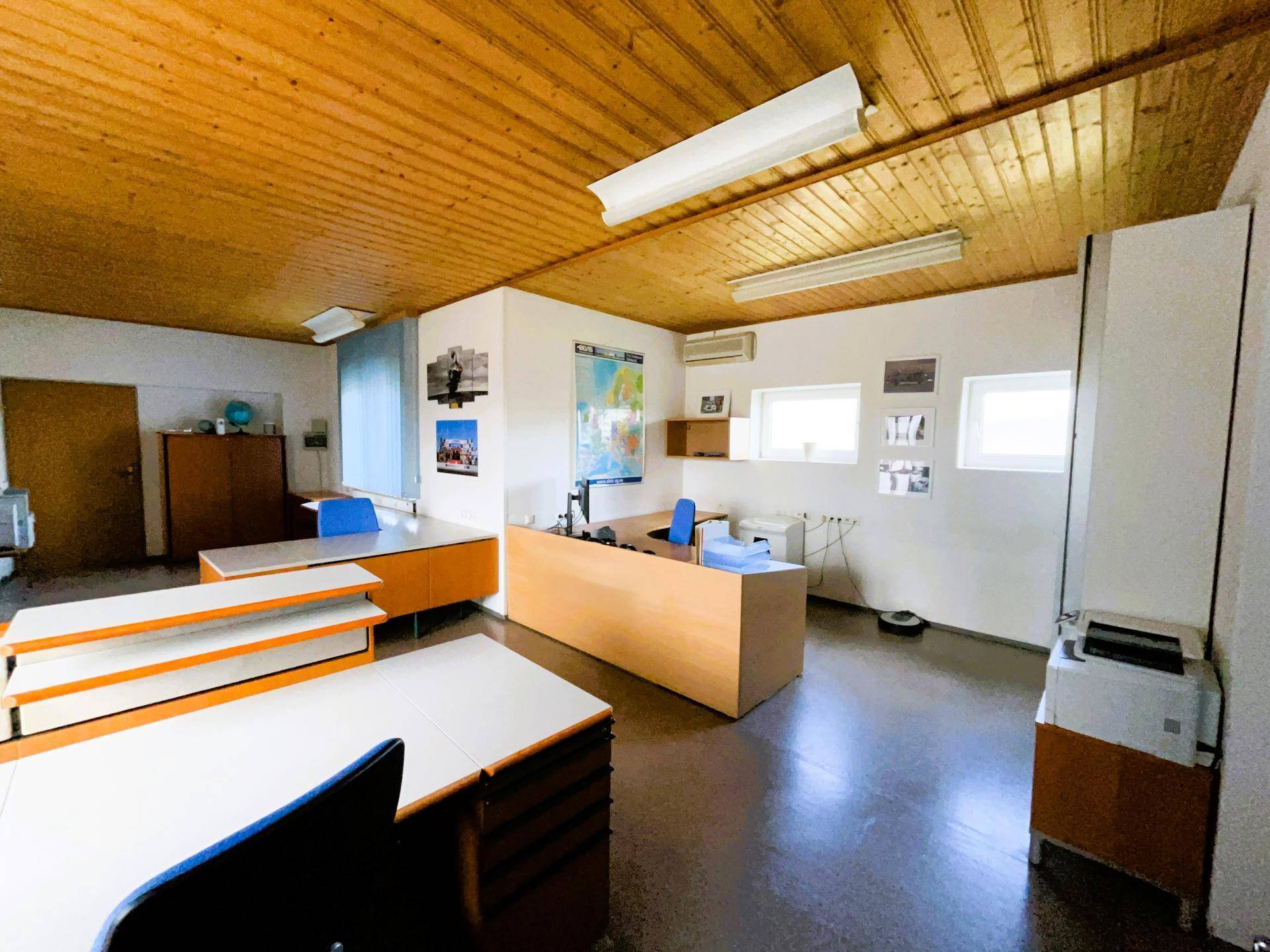 Büro mit Holzdecke und mehreren Arbeitsplätzen, ausgestattet mit Computern und Büromöbeln.