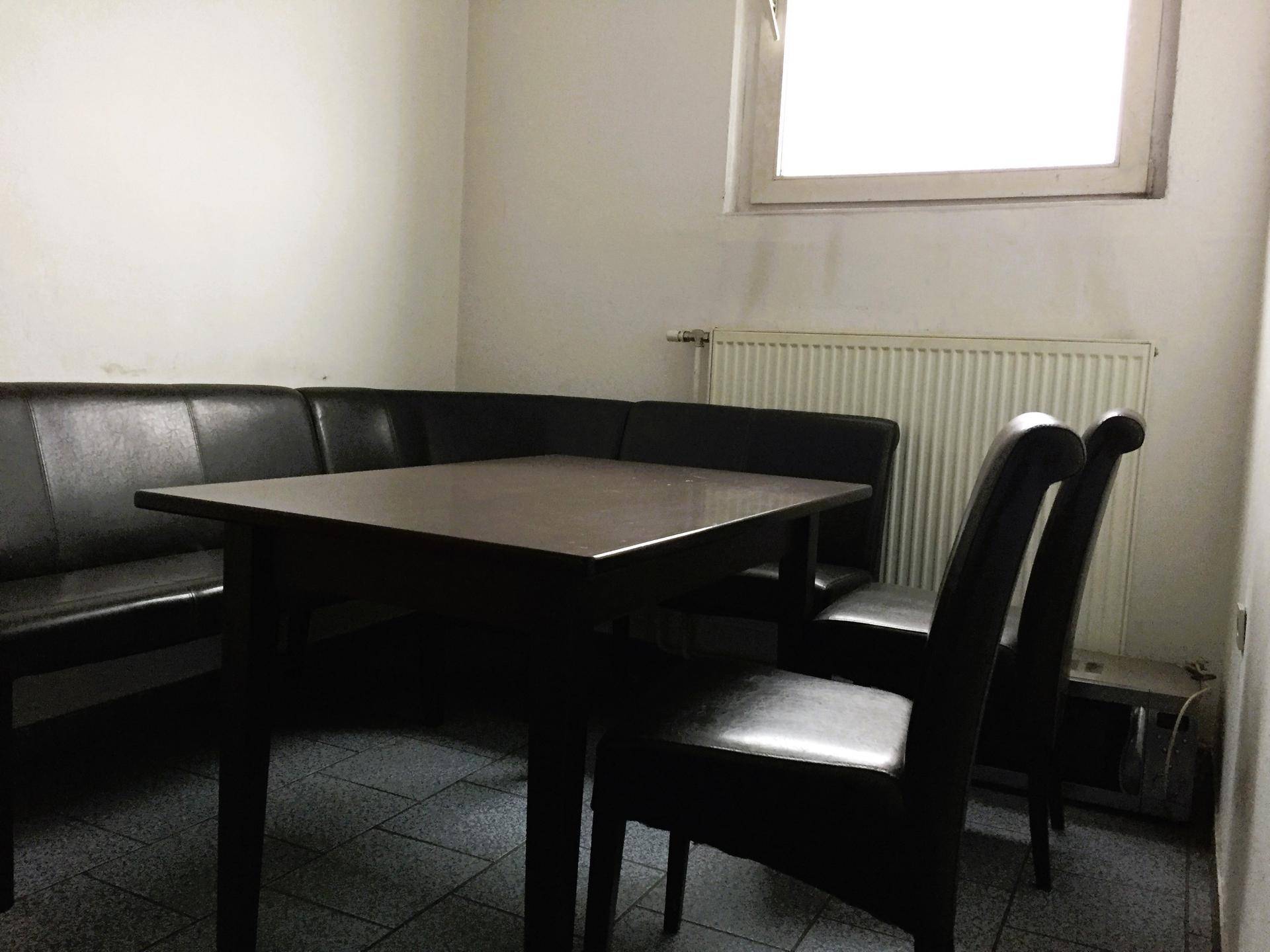 Gemütlicher Essbereich mit Eckbank und Tisch, beleuchtet durch ein kleines Fenster, perfekt für Mitarbeiterpausen.