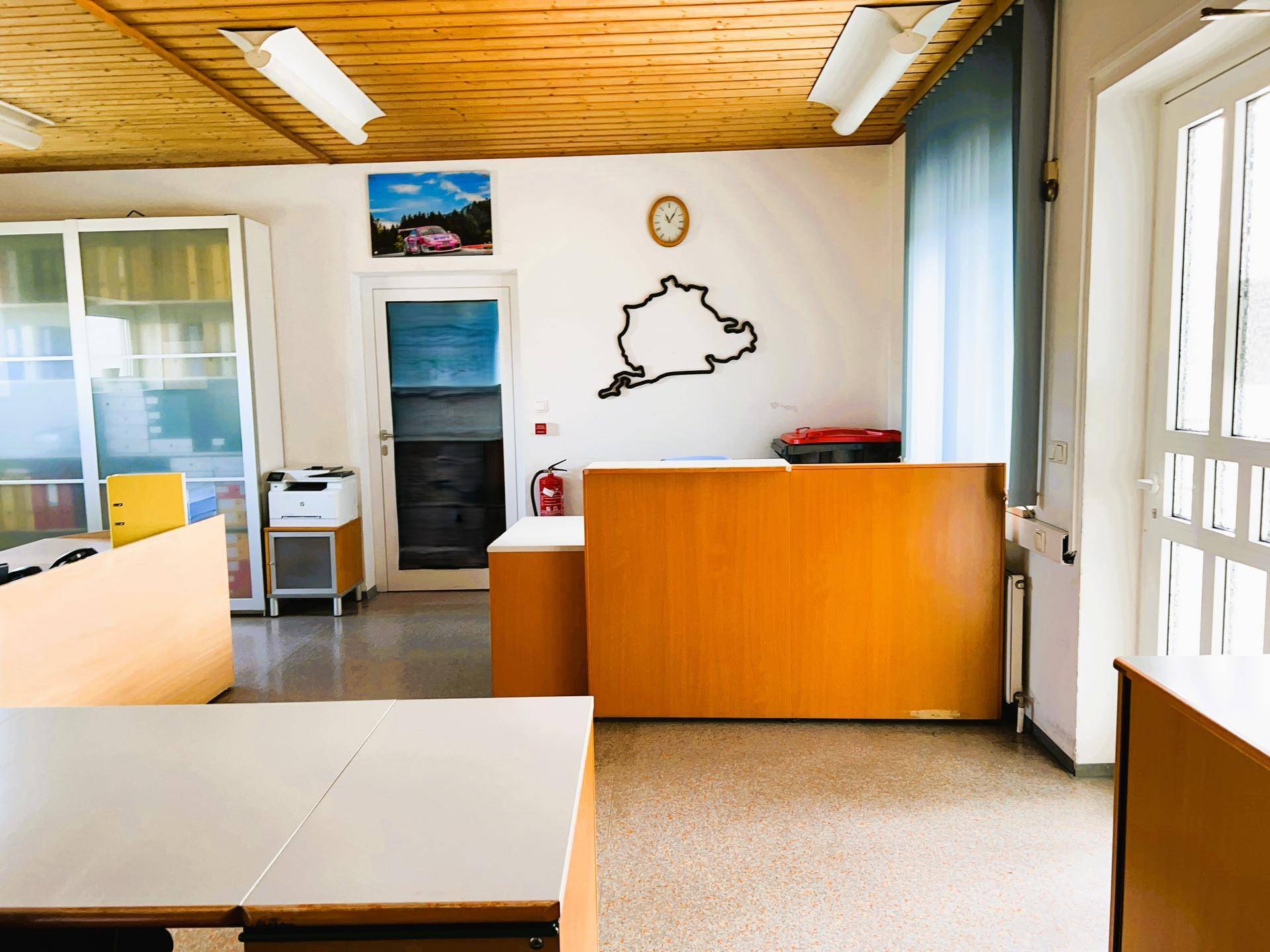 Büro mit Holzdecke und modernen Büromöbeln, darunter ein Schreibtisch und ein Aktenschrank, für eine effiziente Arbeitsumgebung.