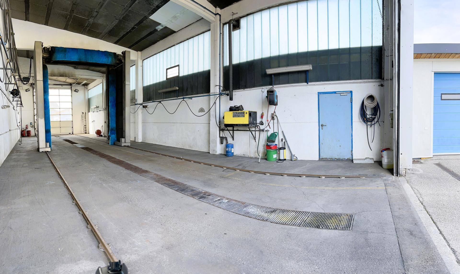 Innenansicht der Autowaschanlage mit blauer Waschanlage und technischer Ausrüstung an der Wand.