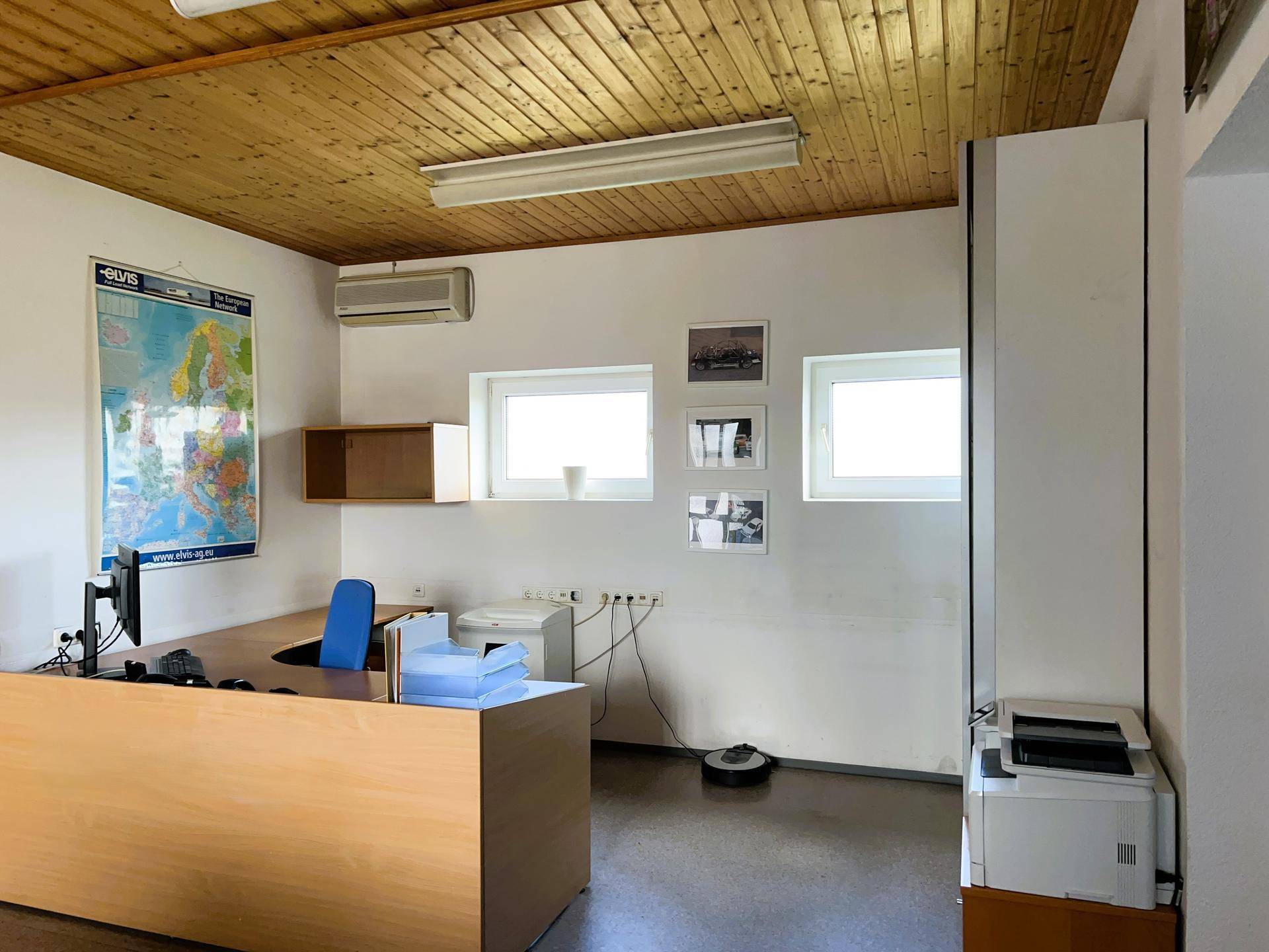 Büro mit Holzdecke, Klimaanlage und mehreren Fenstern, die für ausreichend Tageslicht sorgen.