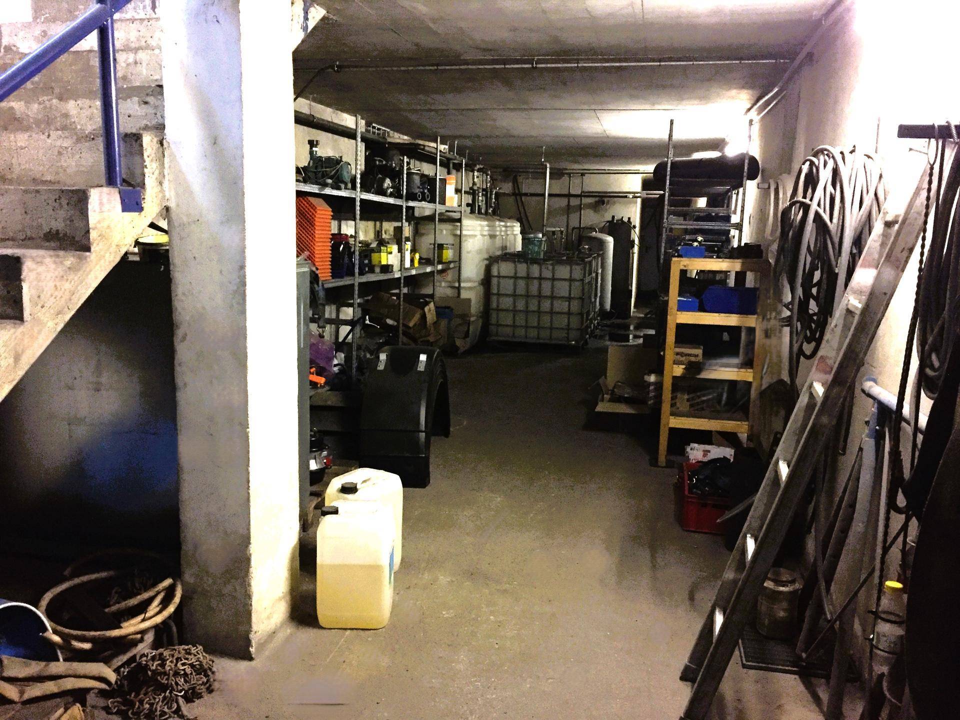 Geräumiger Kellerraum, der als Lager für verschiedene Materialien und Ausrüstungen dient, mit sichtbaren Regalen.