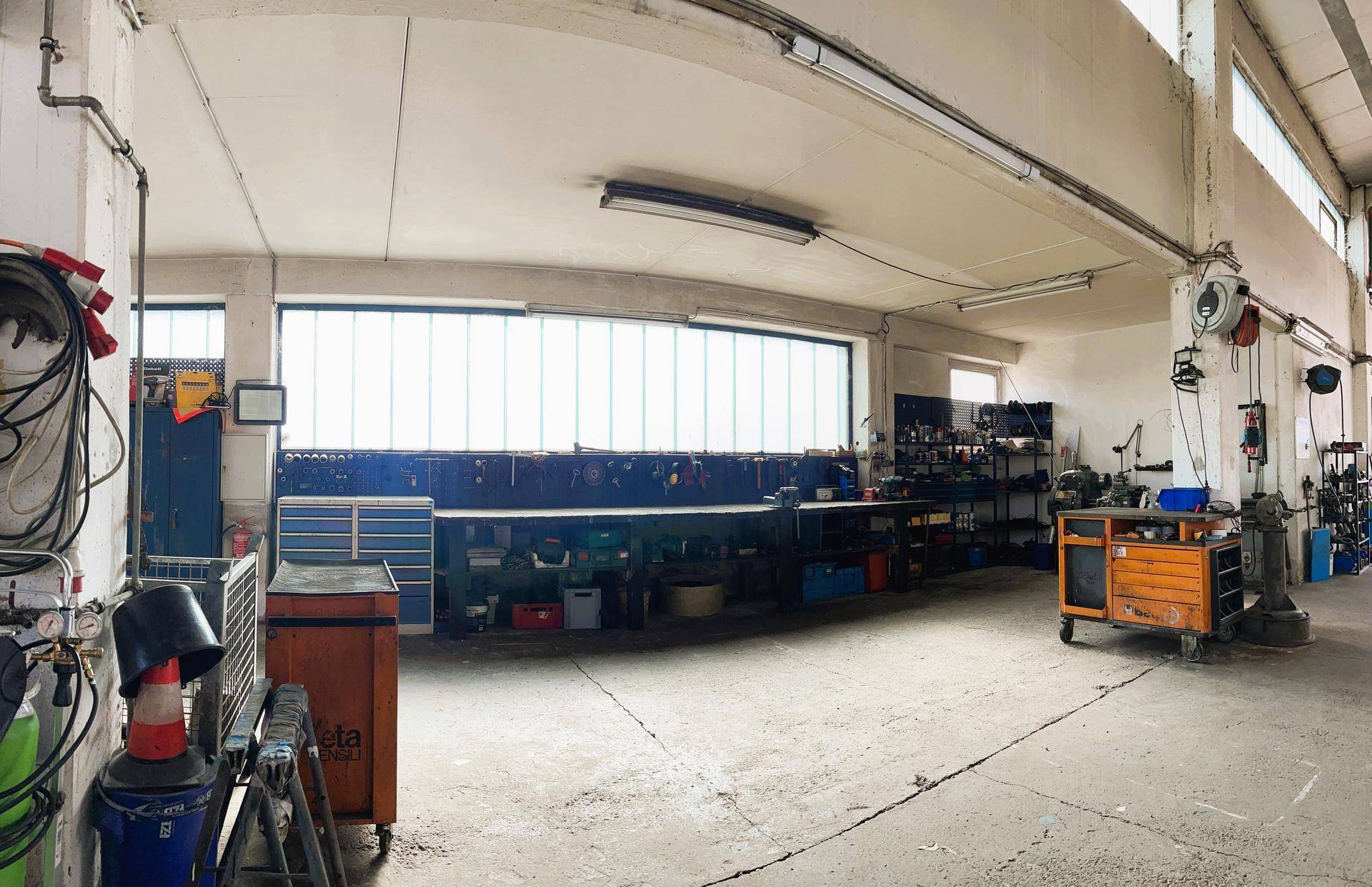 Werkstatthalle mit langen Werkbänken und verschiedenen Werkzeugen, bereit für den täglichen Betrieb.