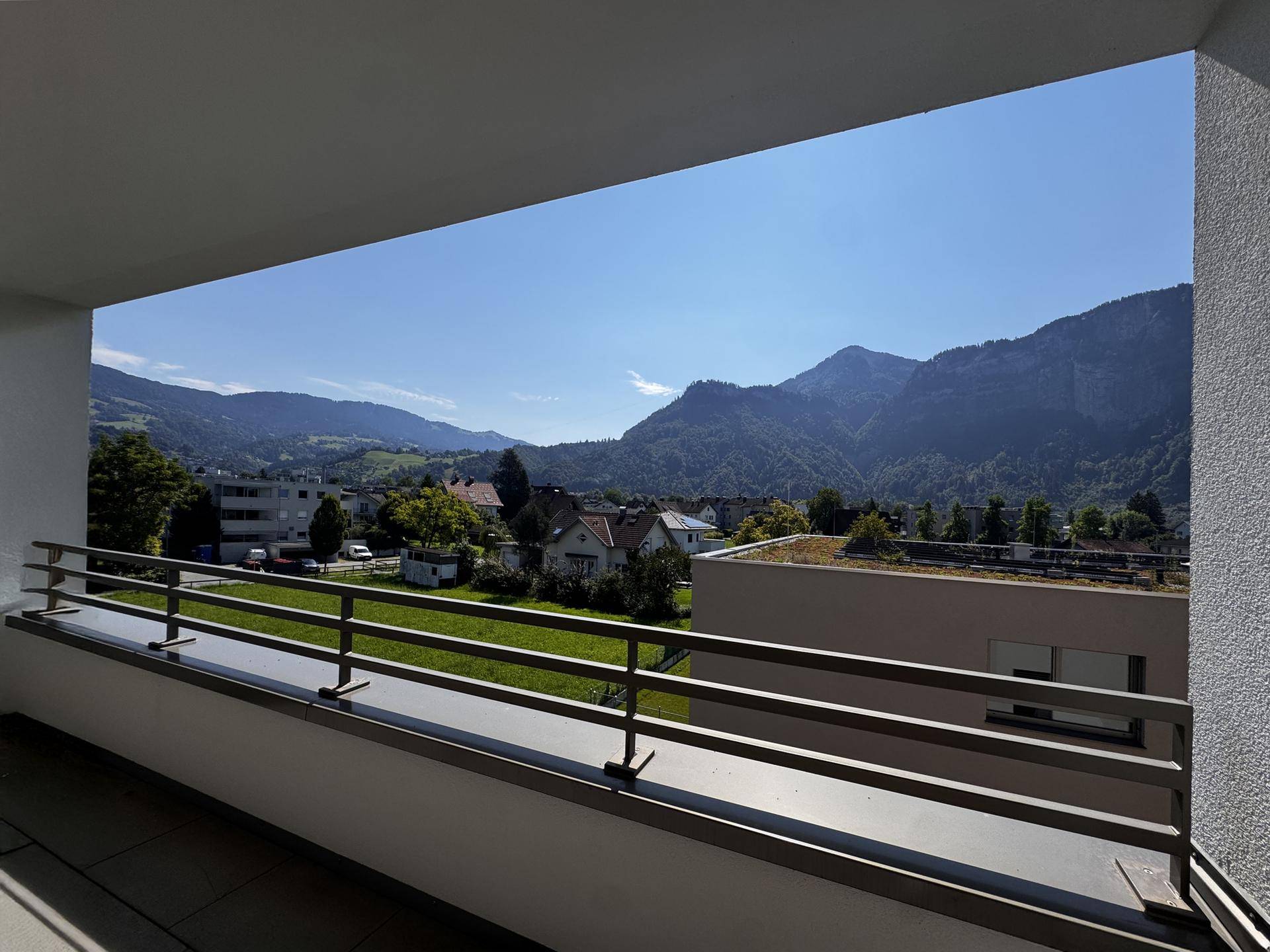 Balkon mit weitem Blick auf die umliegende Berglandschaft und die grüne Umgebung.