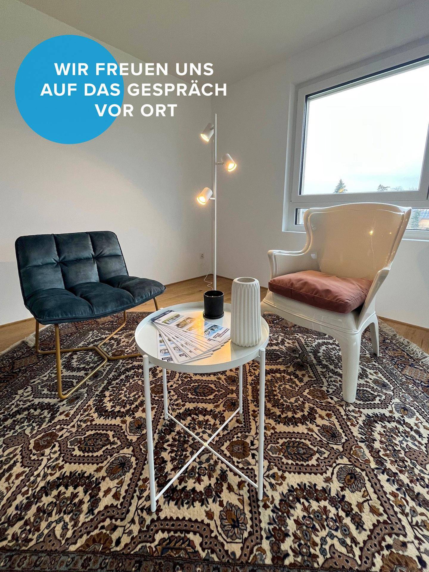 Gemütliche Sitzecke mit zwei Sesseln, Beistelltisch und Stehlampe auf einem orientalischen Teppich.