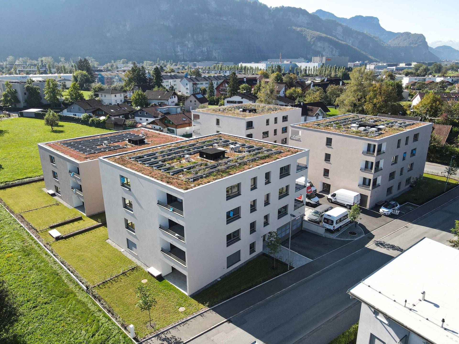 Luftaufnahme einer Wohnanlage mit begrünten Dächern, Solaranlagen und umliegender Natur.