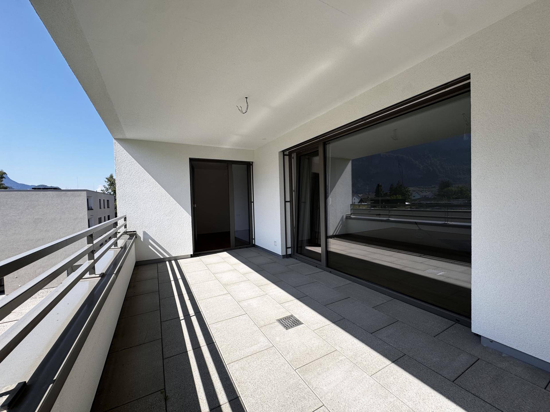 Geräumiger Balkon mit Fliesenboden und großen Glasfronten, ideal für entspannte Stunden im Freien.