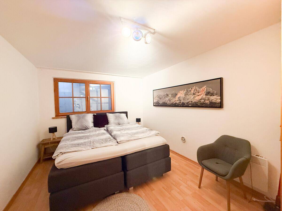 Gemütliches Schlafzimmer mit Doppelbett, Holzboden und einem Fenster.