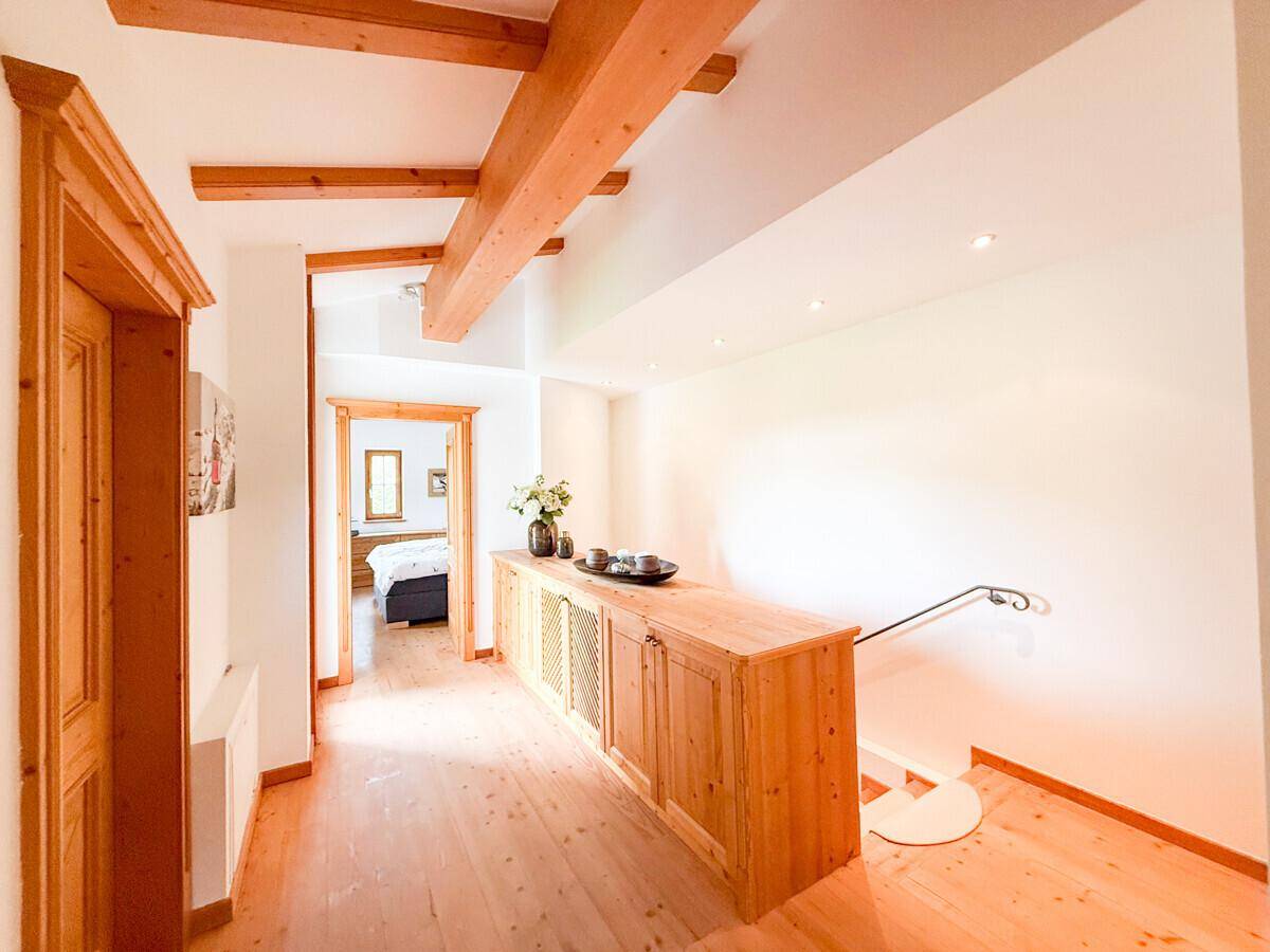 Heller Flur mit Holzboden, sichtbaren Holzbalken und einer Holzkommode.