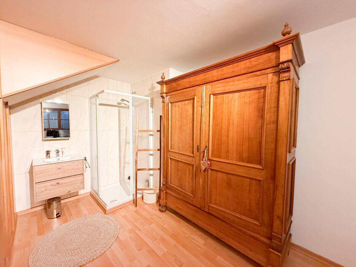 Badezimmer mit Duschkabine, modernem Waschtisch und einem großen Holzschrank.