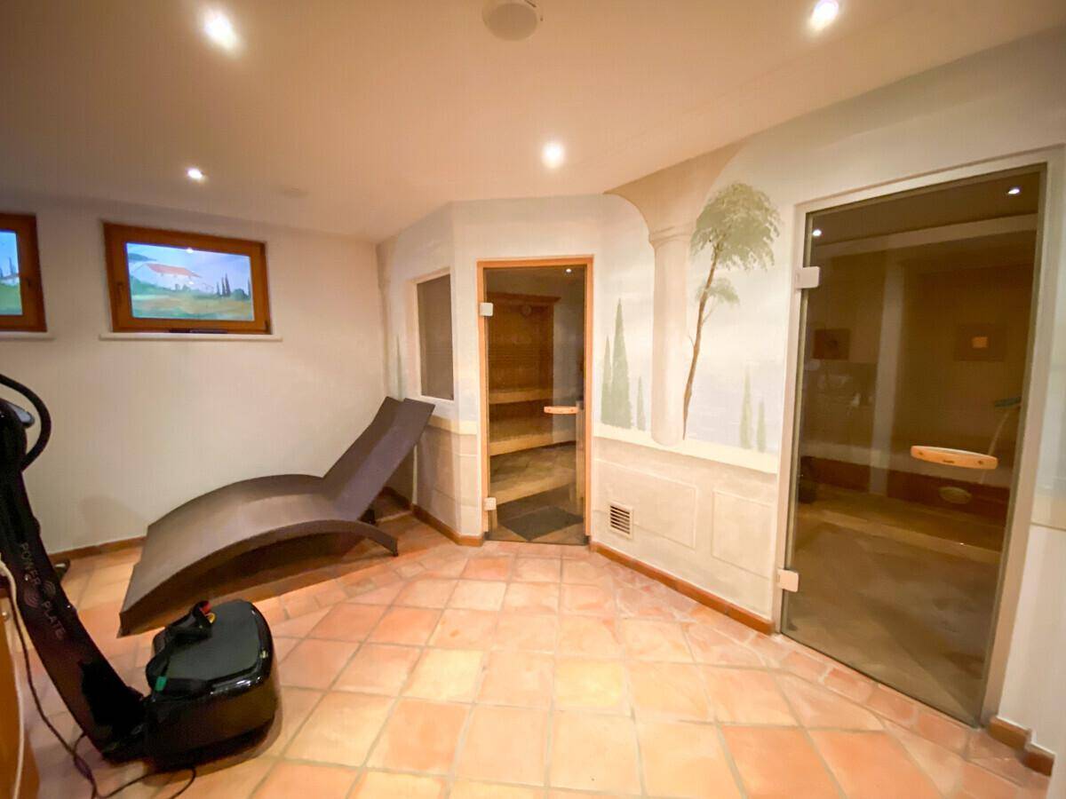 Entspannender Wellnessbereich mit Sauna, Liege und Fliesenboden.